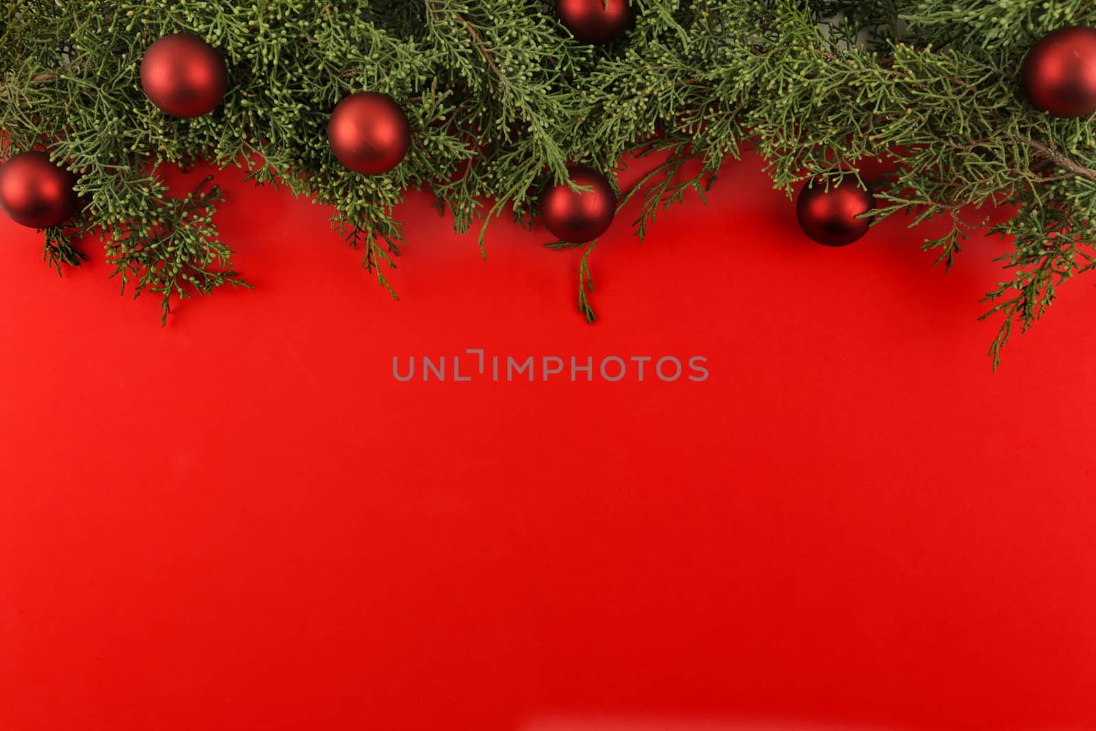 Flat lay red Christmas copy space with pine branches and red Christmas baubles on top by robbyfontanesi