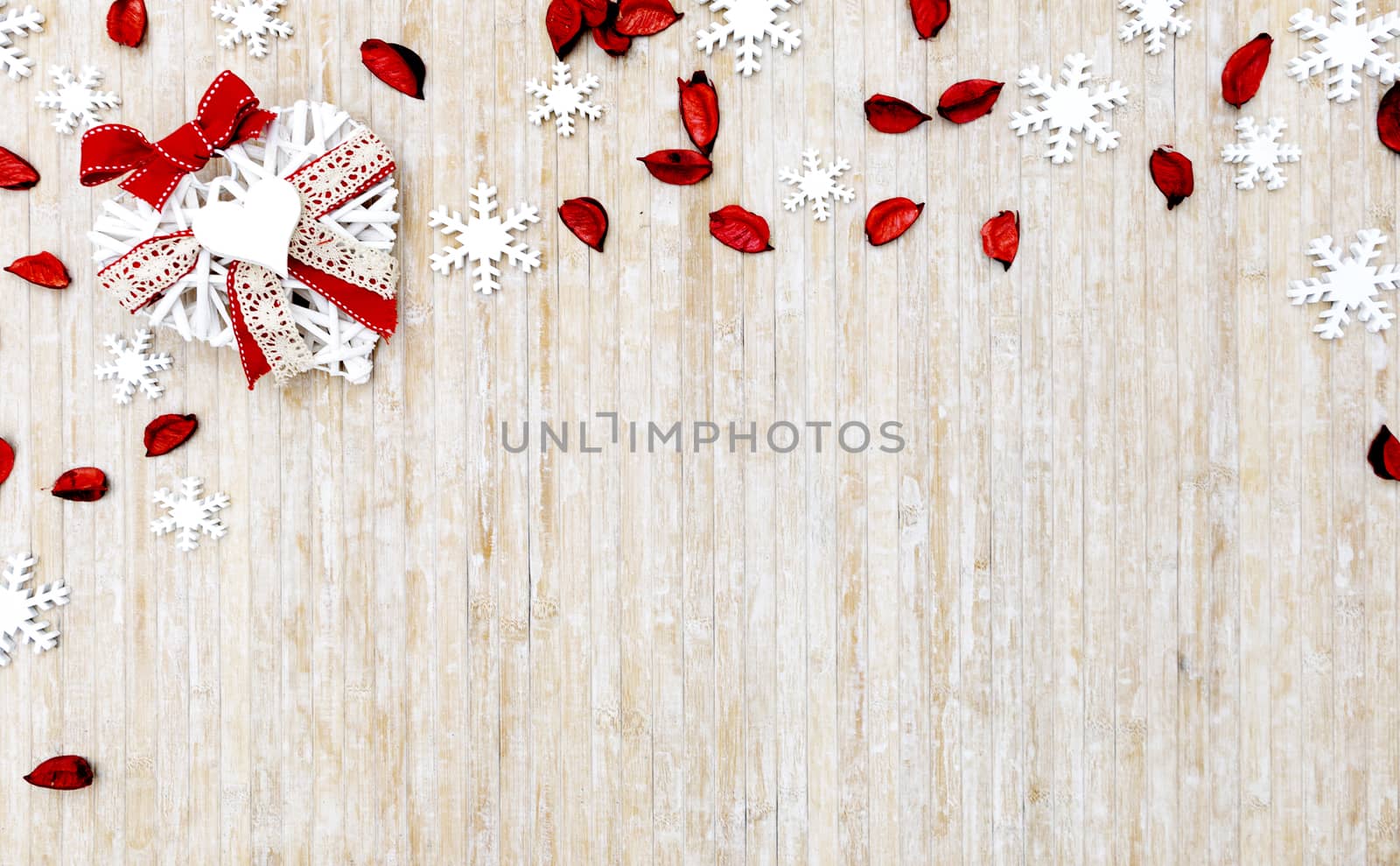 Flat lay shabby Christmas copy space with white wooden snowflakes, red petals and a white wooden decorative heart in the upper left corner on light wooden background by robbyfontanesi