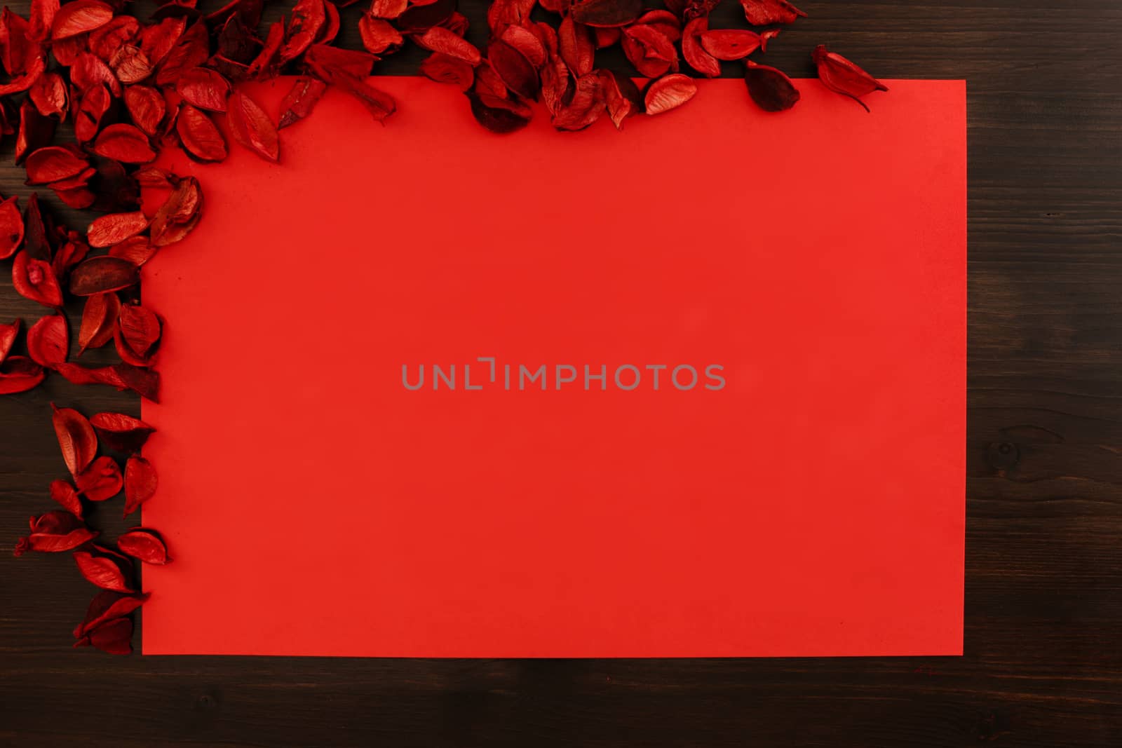 Flat lay red Christmas copy space with red petals in the upper left corner and dark wood all around by robbyfontanesi