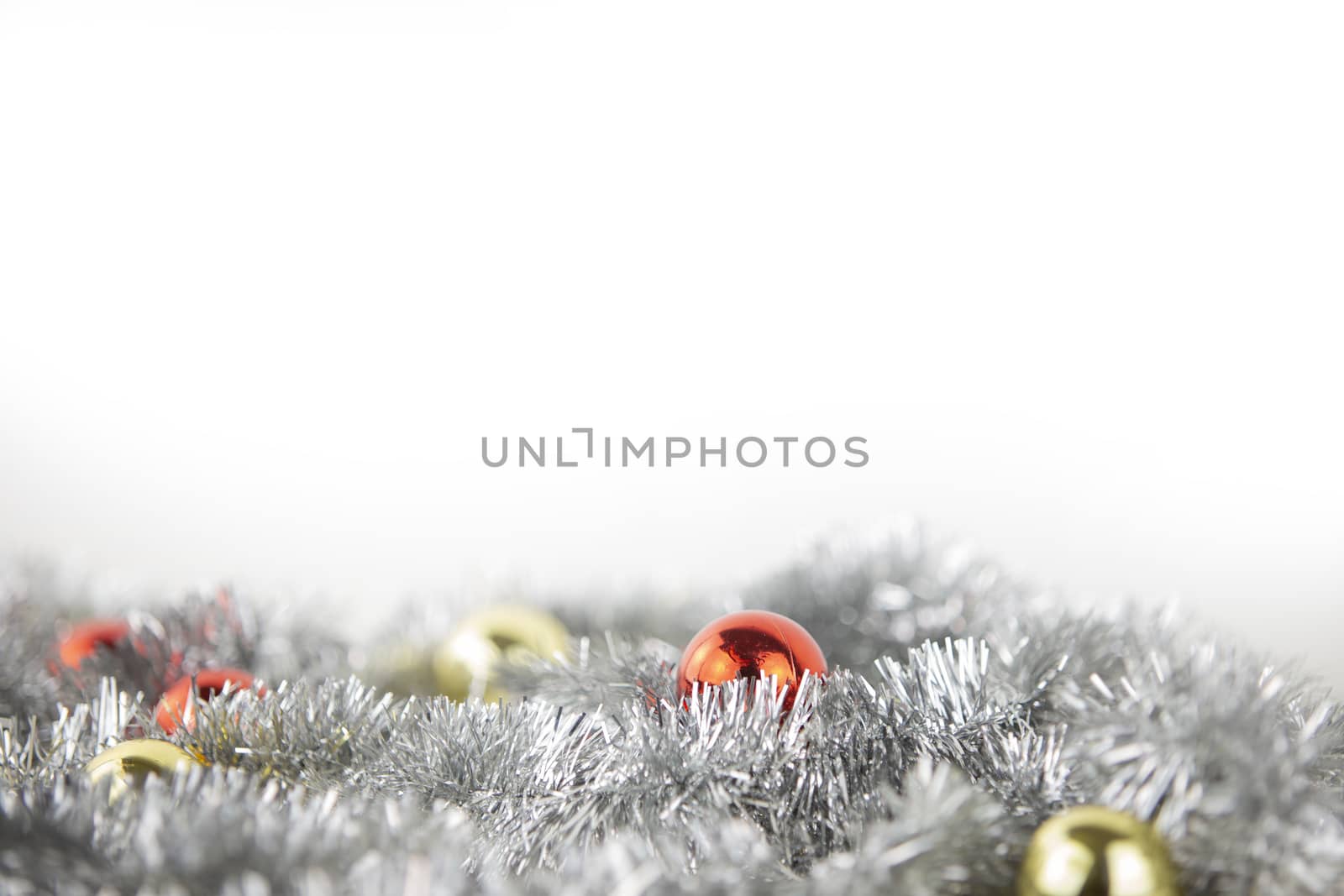 Christmas copy space with red and gold bright baubles in silver decorative chain on bottom on white background and bokeh effect