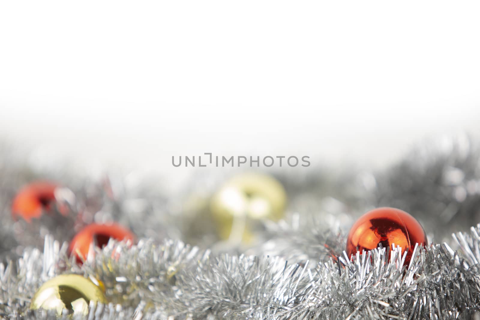 Christmas copy space with red and gold bright baubles in silver decorative chain on bottom on white background and bokeh effect by robbyfontanesi