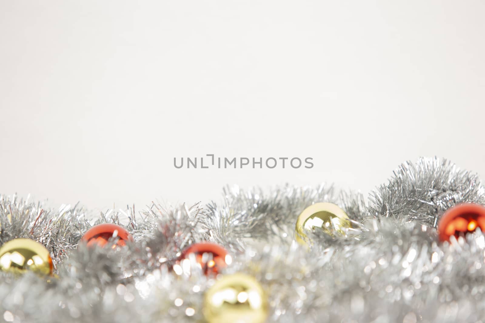 Christmas copy space with red and gold bright baubles in silver decorative chain on bottom on white background and bokeh effect