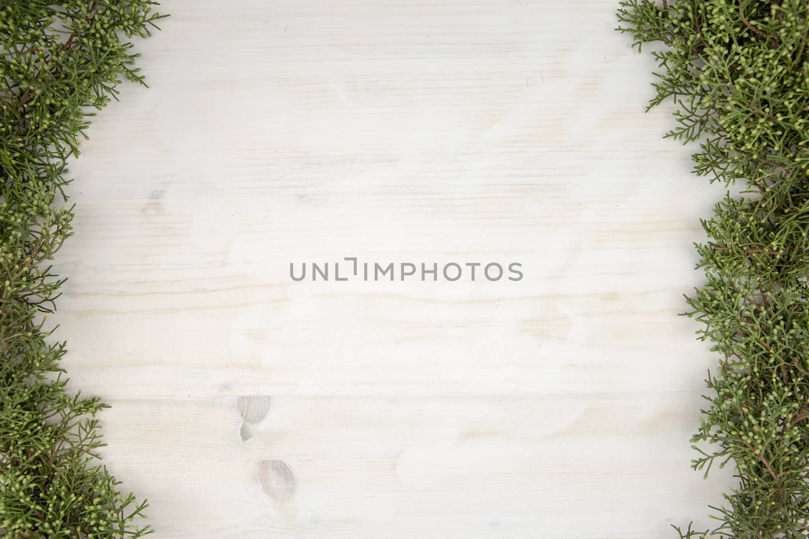 Flat lay Christmas copy space with pine branches on the sides on light wooden background by robbyfontanesi