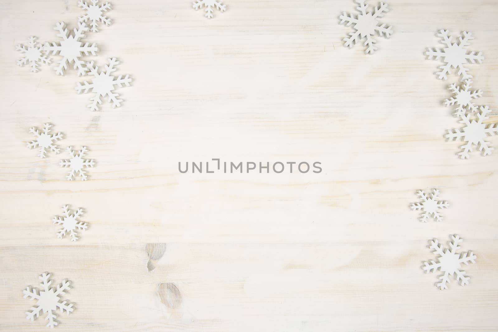 Flat lay Christmas copy space with white wooden snowflakes on a light wooden background by robbyfontanesi