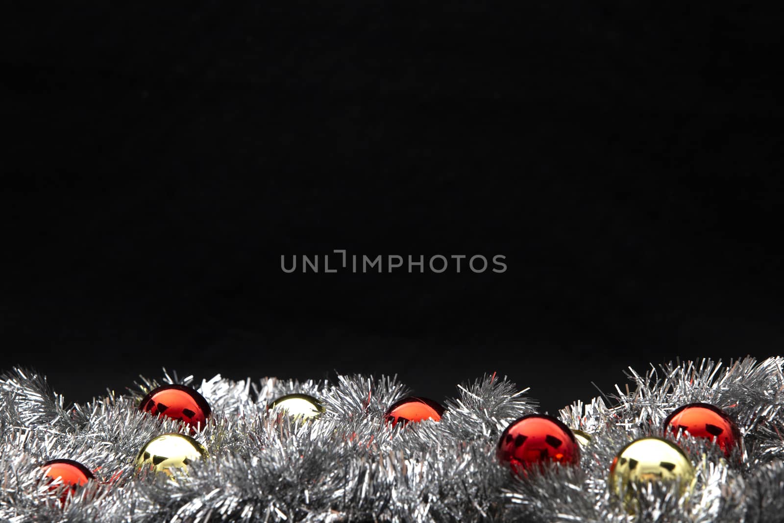 Christmas copy space with red and gold bright baubles in silver decorative chain on bottom on white background and bokeh effect