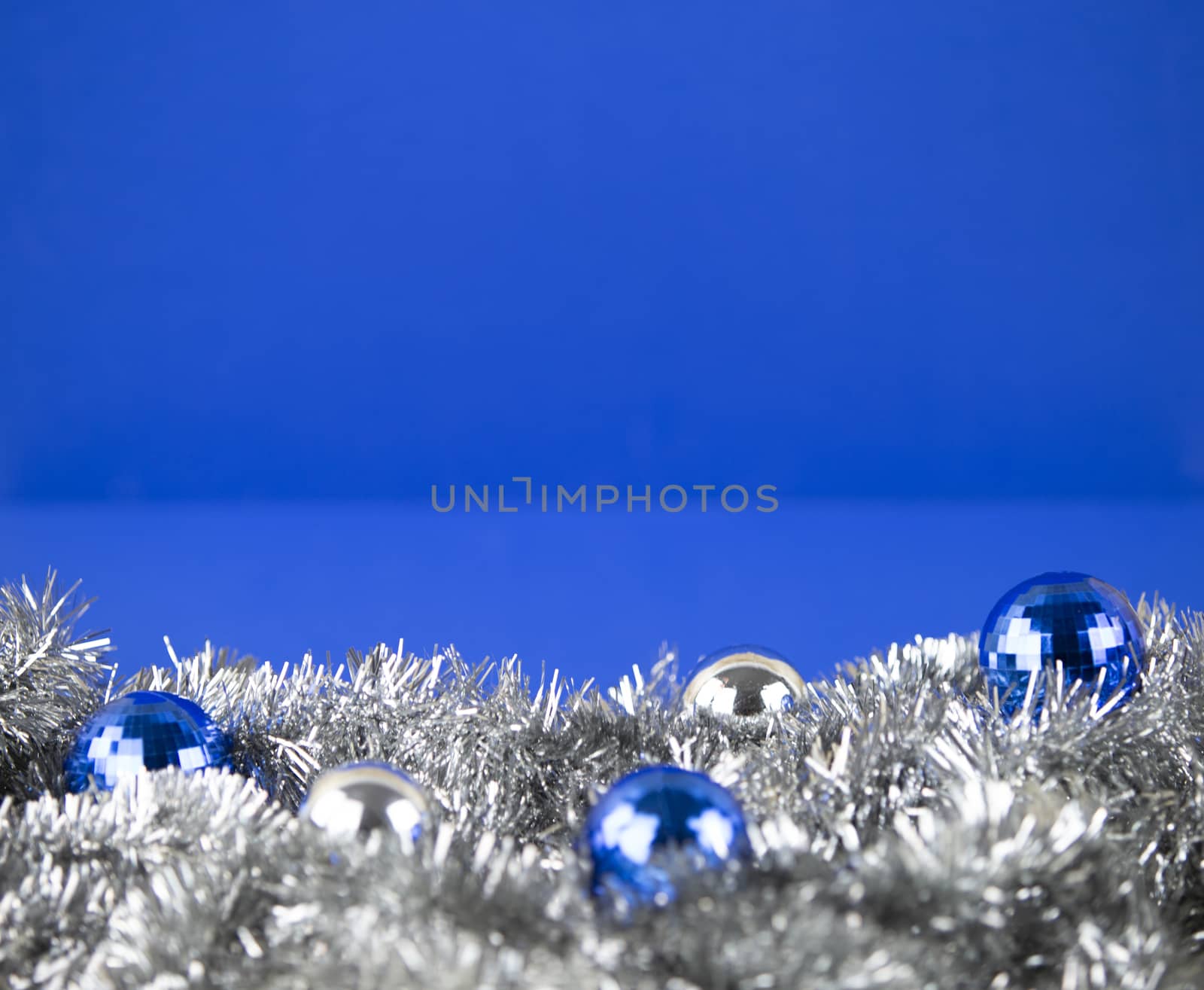 Christmas copy space with blue and silver bright baubles in silver decorative chain garland on blue background with bokeh effect