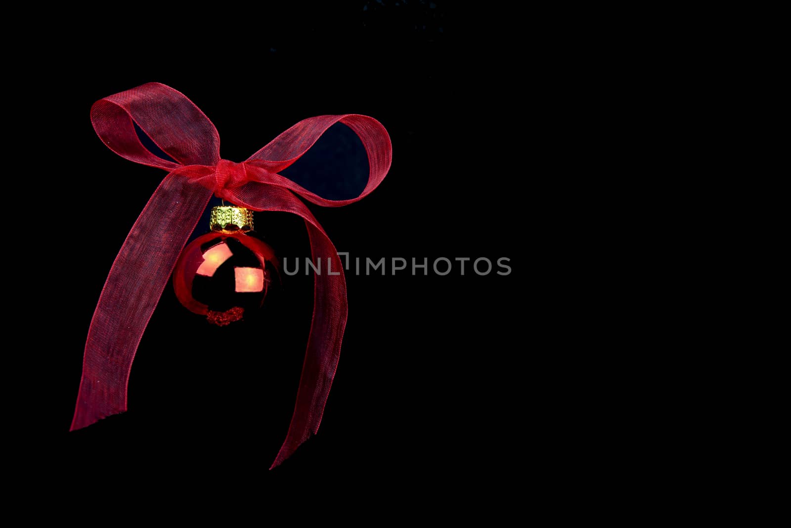 Black Christmas copy space with red ball hanging with a red organza bow on black background