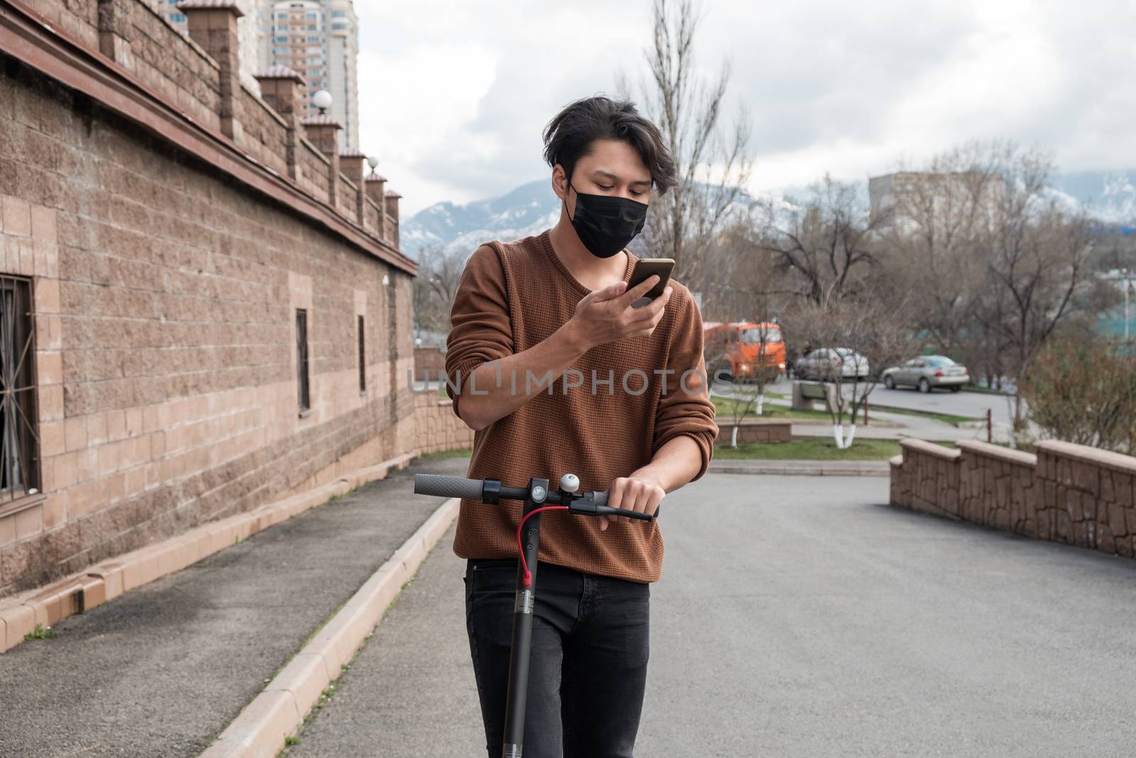 Young man riding a scooter and talking by mobile phone in the city