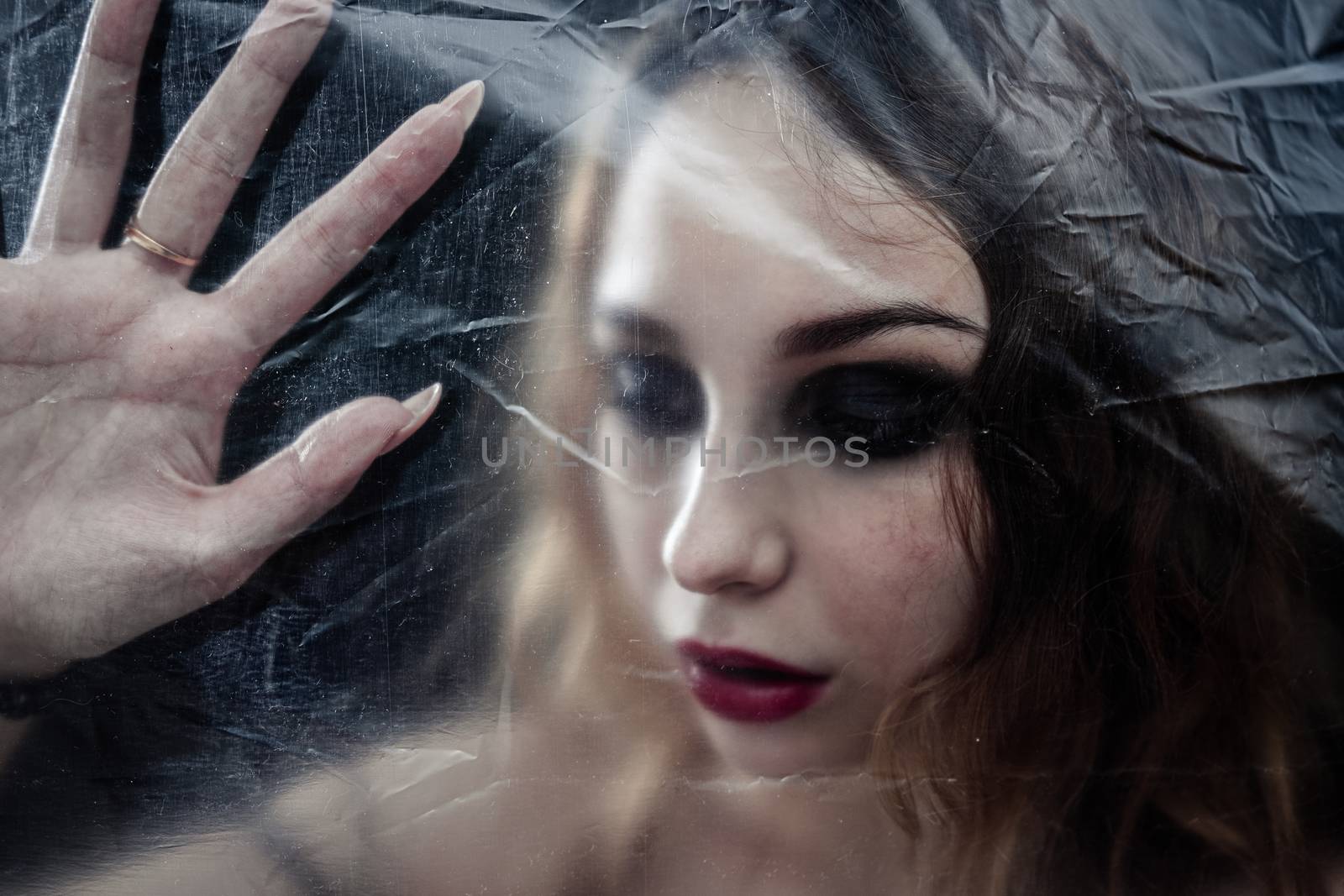 Young beauty sad woman trapped behind a plastic sheet as protect by snep_photo