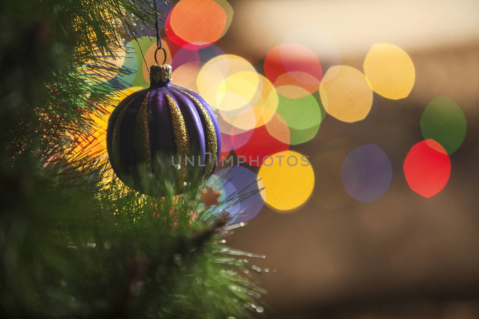 A Christmas bauble hangs from a tree and light on a background