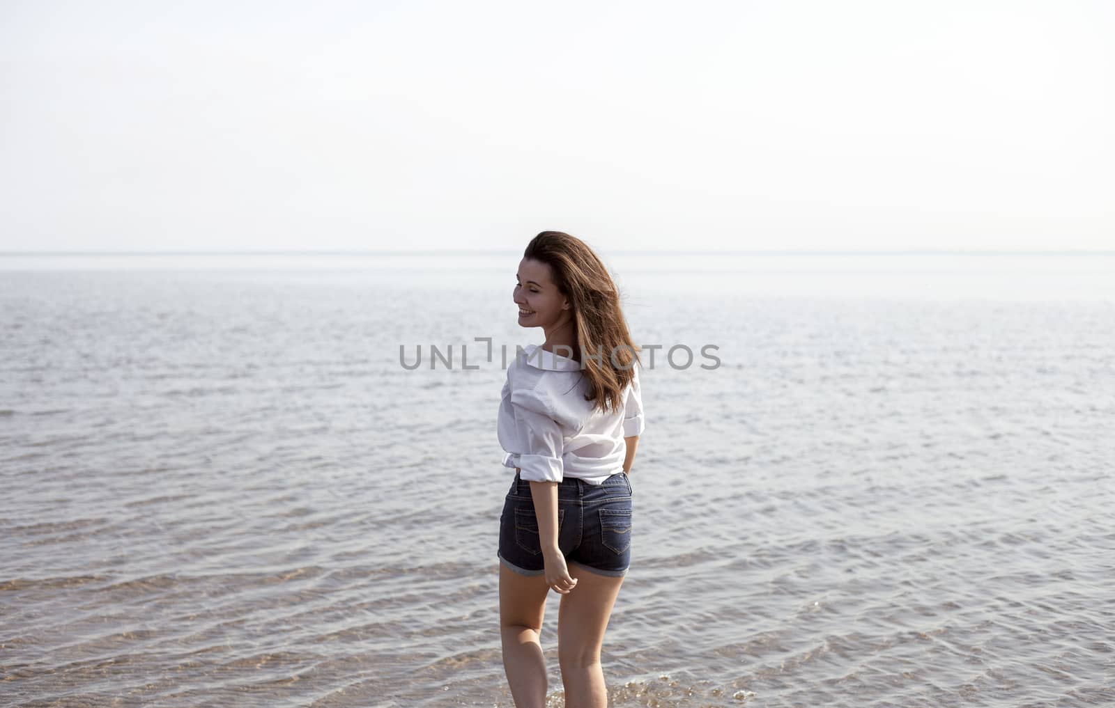 Smiling young woman enjoying her summer vacation on the beach. Beautiful female model having fun on the sea shore.