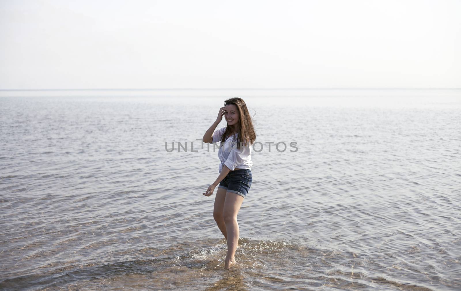 Smiling young woman enjoying her summer vacation on the beach. Beautiful female model having fun on the sea shore.