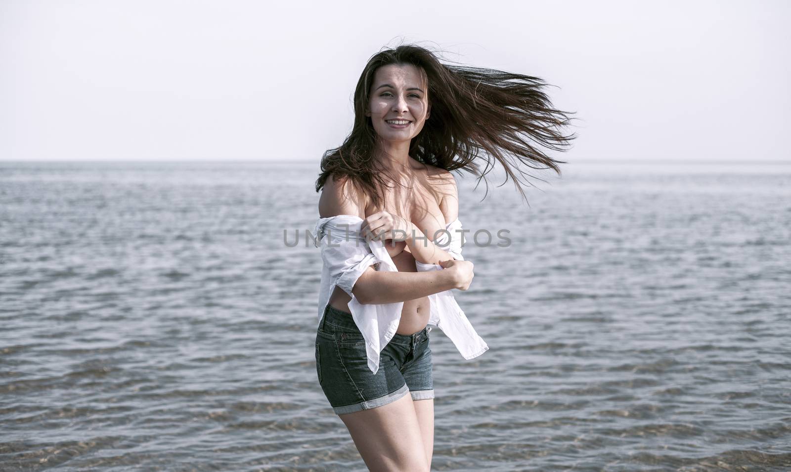 Smiling young woman enjoying her summer vacation on the beach. Beautiful female model having fun on the sea shore.