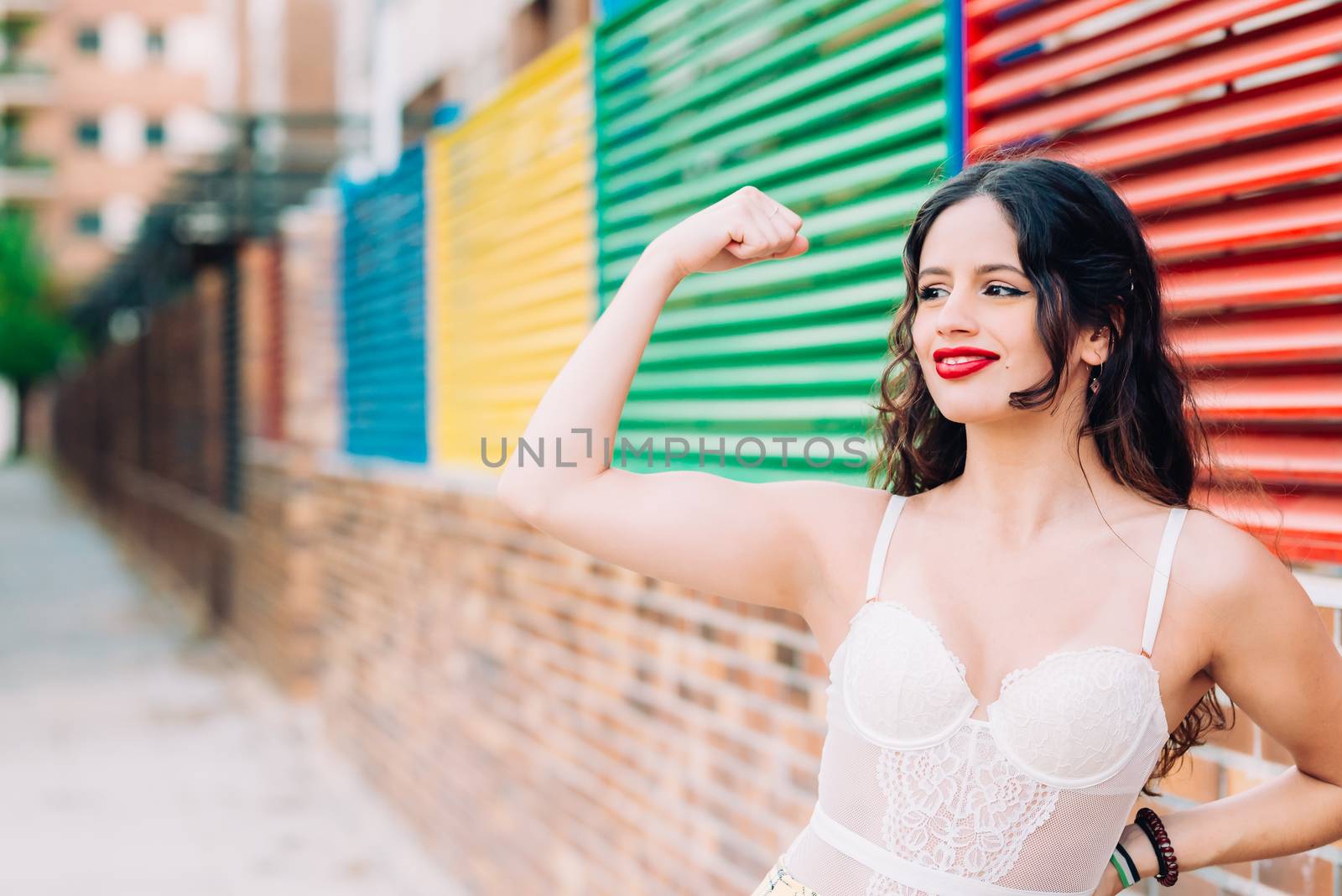 Powerful young woman in a success pose on street.