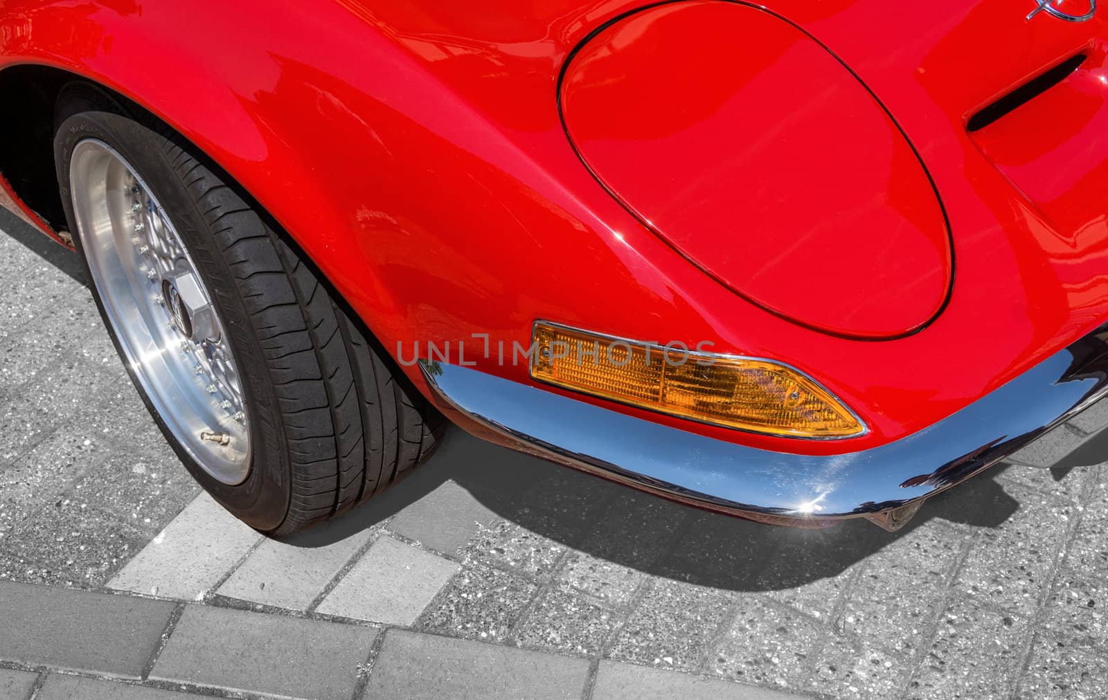 Detail view, from the right front corner of a red sports car with folding headlights, indicators,. bumper and a part of the front wheel, Germany