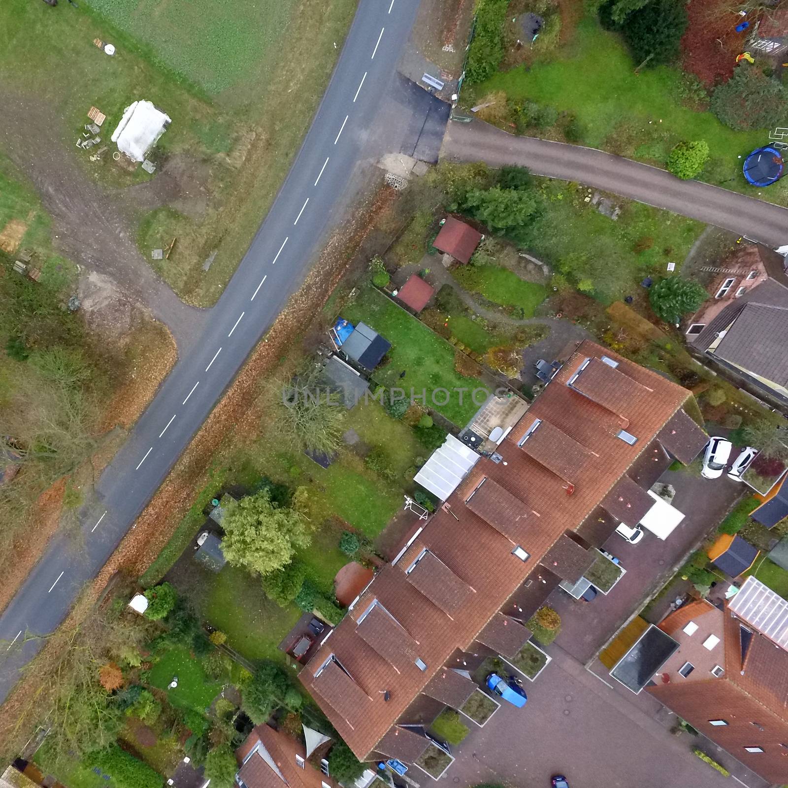 Aerial view of a terraced house with garden and lawn next to a country road without cars by geogif