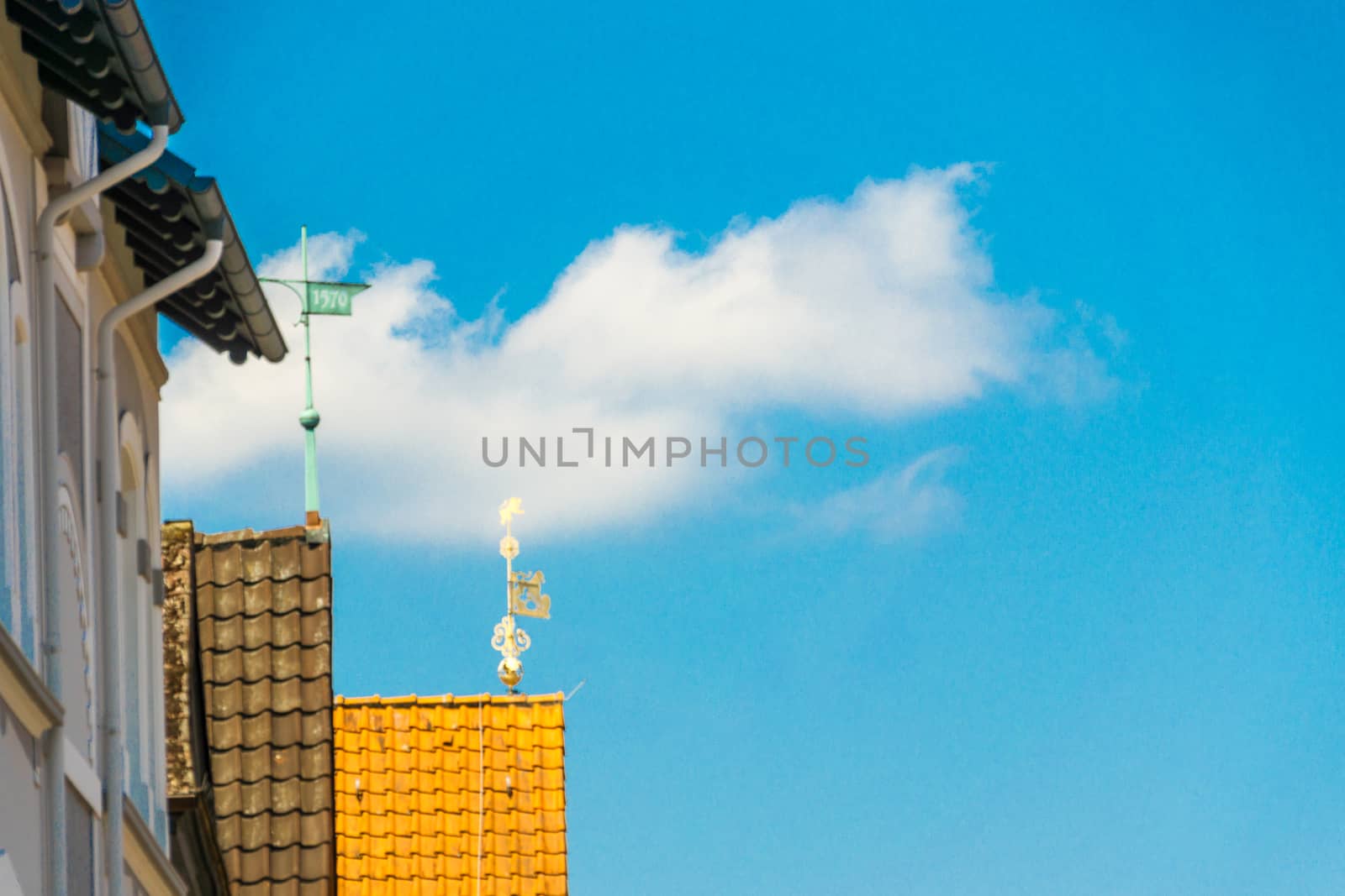 Artistic abstract picture of a small cloud in the blue sky above the roofs of medieval houses in a small town by geogif
