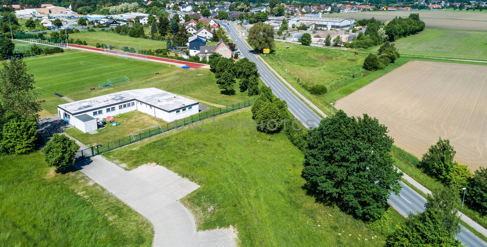 Aerial view of the clubhouse of a regional football club on the outskirts of the city next to a big street, football field in the background, near Wolfsburg