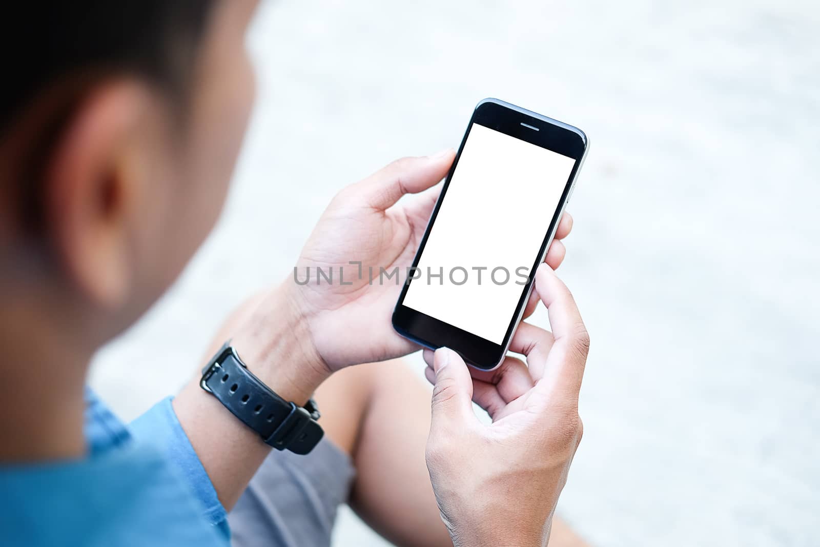 Cropped shot view of man hands holding smart phone with blank copy space screen for your text message or information content, female reading text message on cell telephone during in urban setting. 