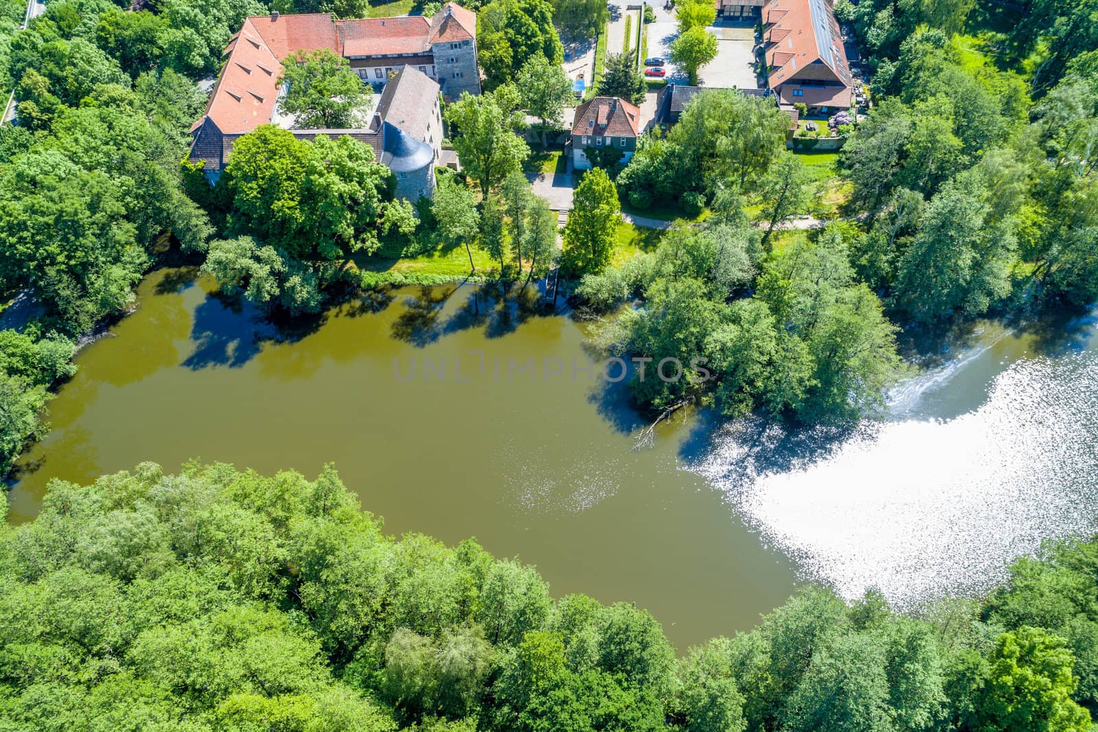 The pond at the moated castle Neuhaus from the air, with bushes and trees, at the edge of the village, near Wolfsburg