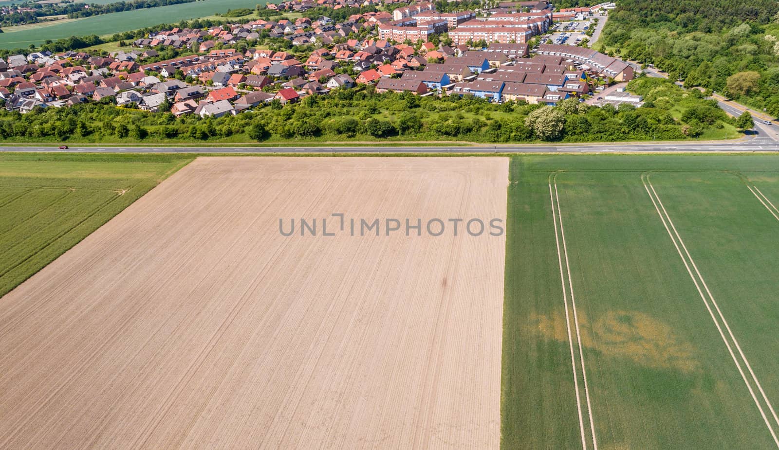 Aerial view of a suburb on the outskirts of Wolfsburg in Germany, with terraced houses, semi-detached houses and detached houses, arable land in the foreground, made with drone