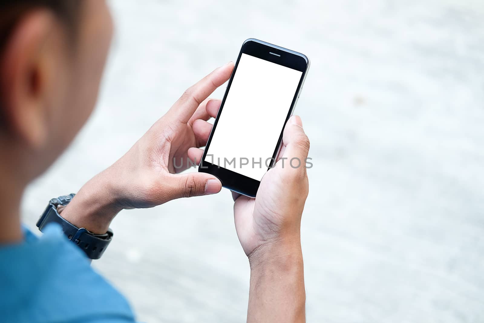 Cropped shot view of man hands holding smart phone with blank copy space screen for your text message or information content, female reading text message on cell telephone during in urban setting. 