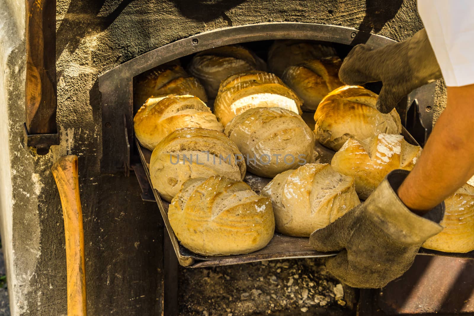 Freshly baked bread on a baking tray at an oven with firewood by geogif