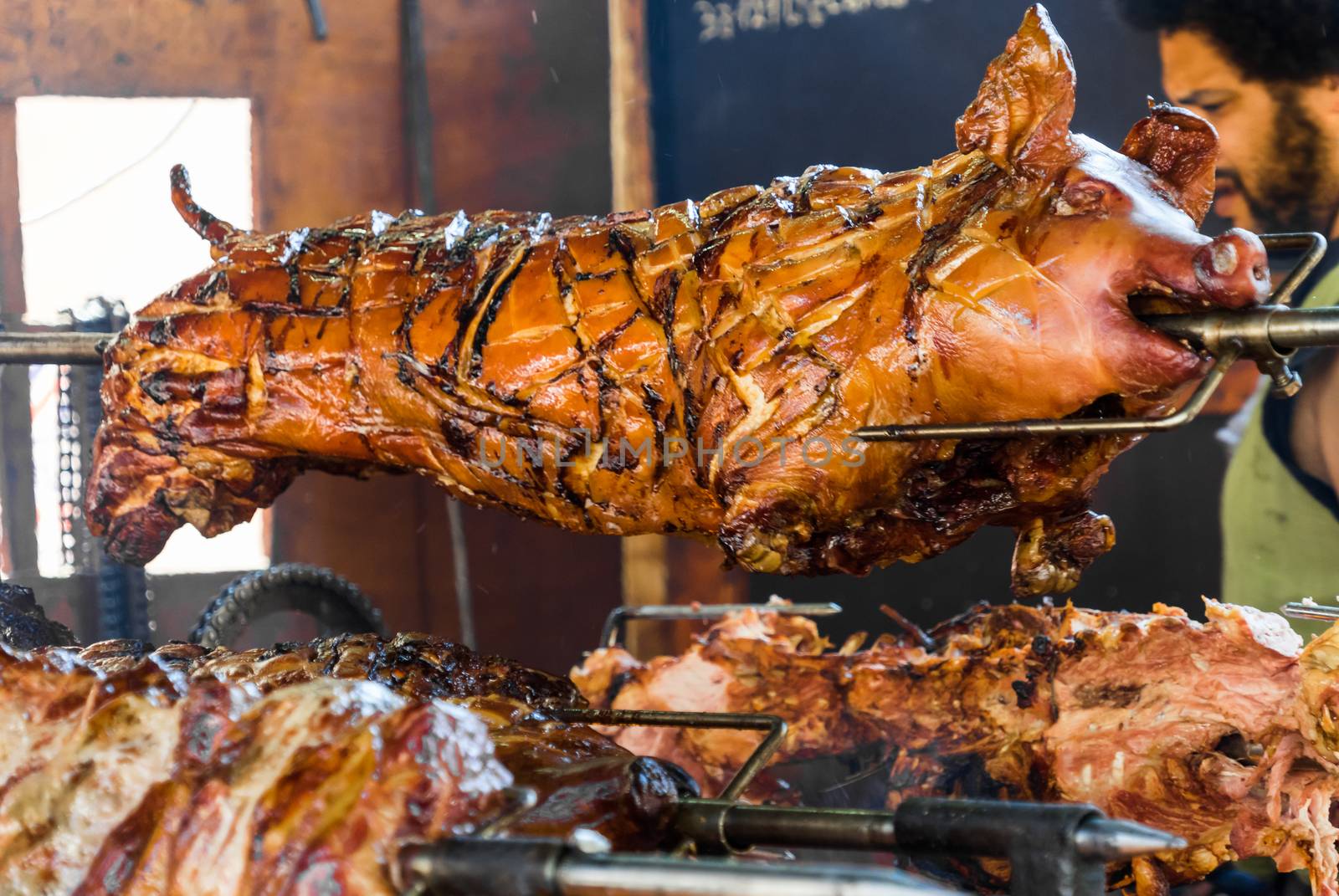 Close-up of the head of a whole pig grilled on a spit over an open fire of logs of wood, Germany