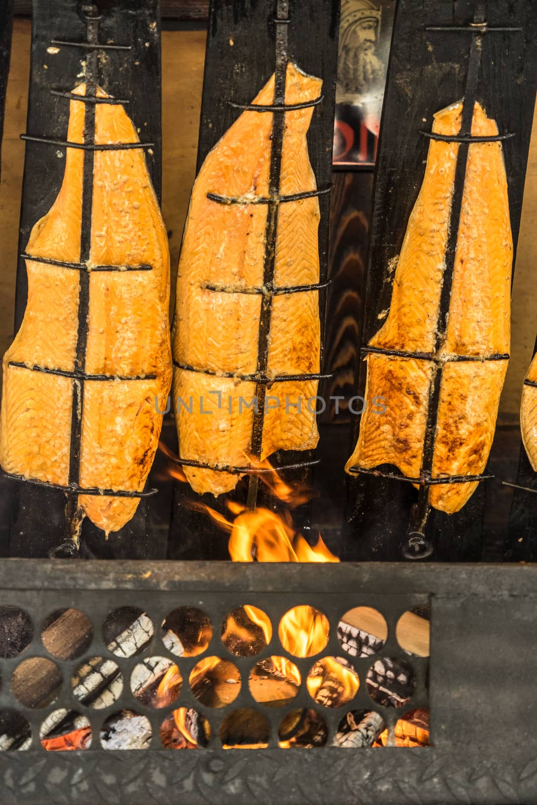 Preparation of flame salmon over the open fire of an open fireplace loaded with wood, Germany