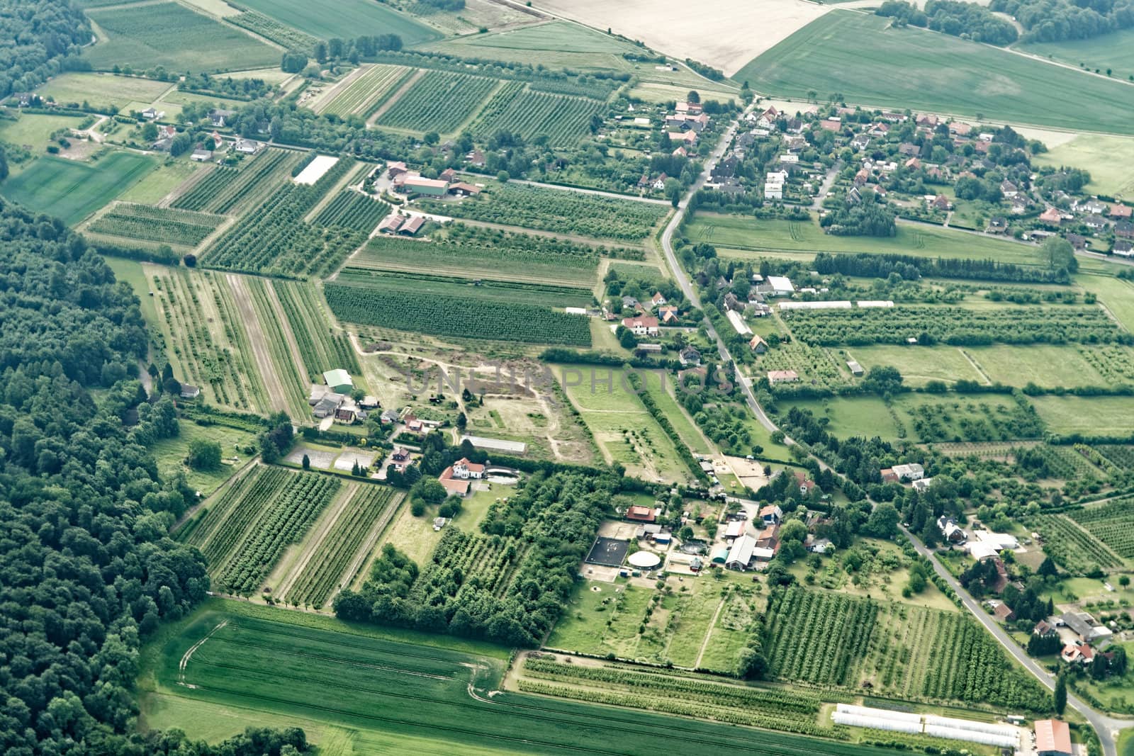 Urban sprawl in the north of Germany with small farmland, roads, houses, commercial enterprises and incoherent woodlands, aerial view