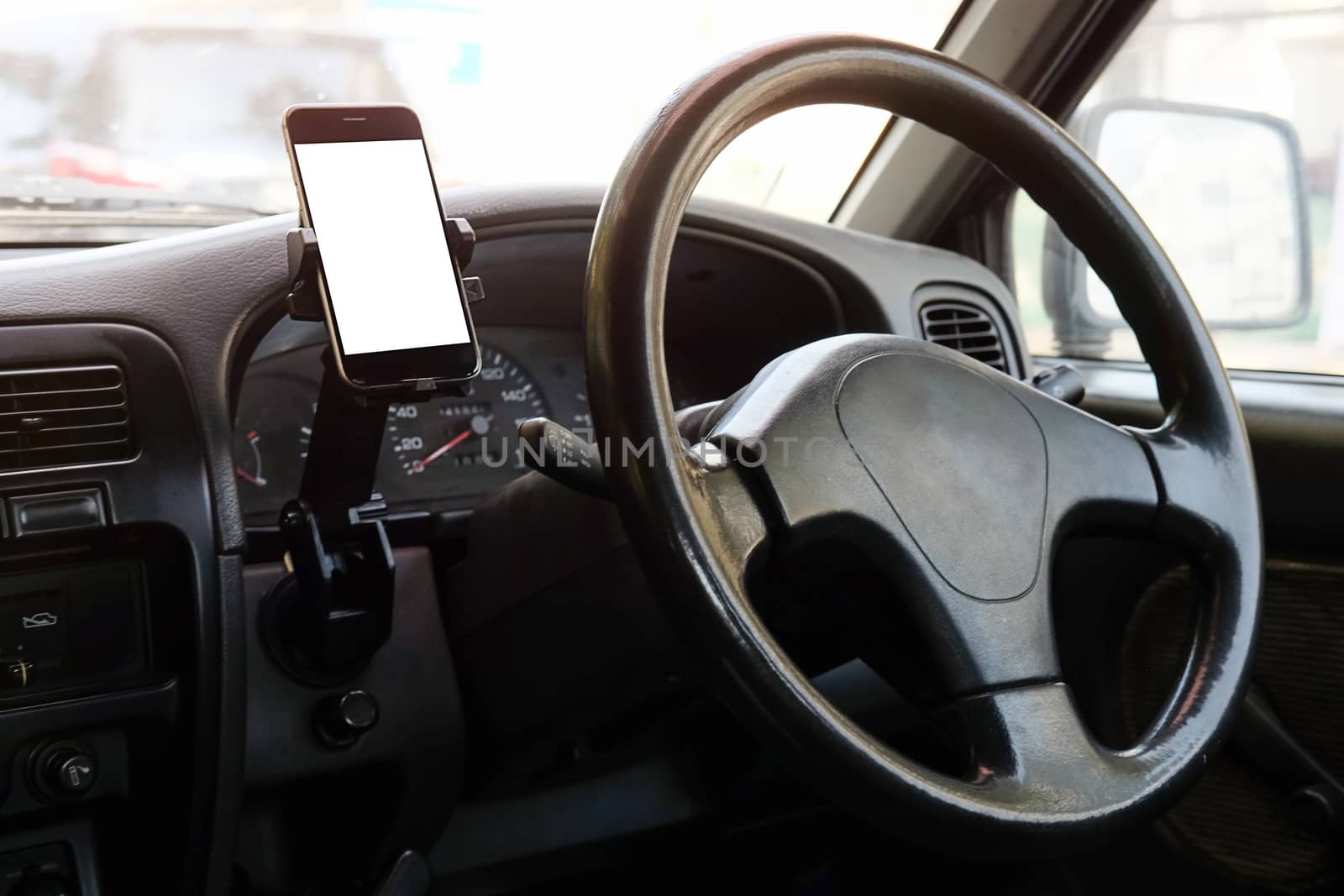 Cropped shot view The driver uses the phone while driving. Modern smart phone with round edges. Isolated screen for mockup. Car navigation display in background. 