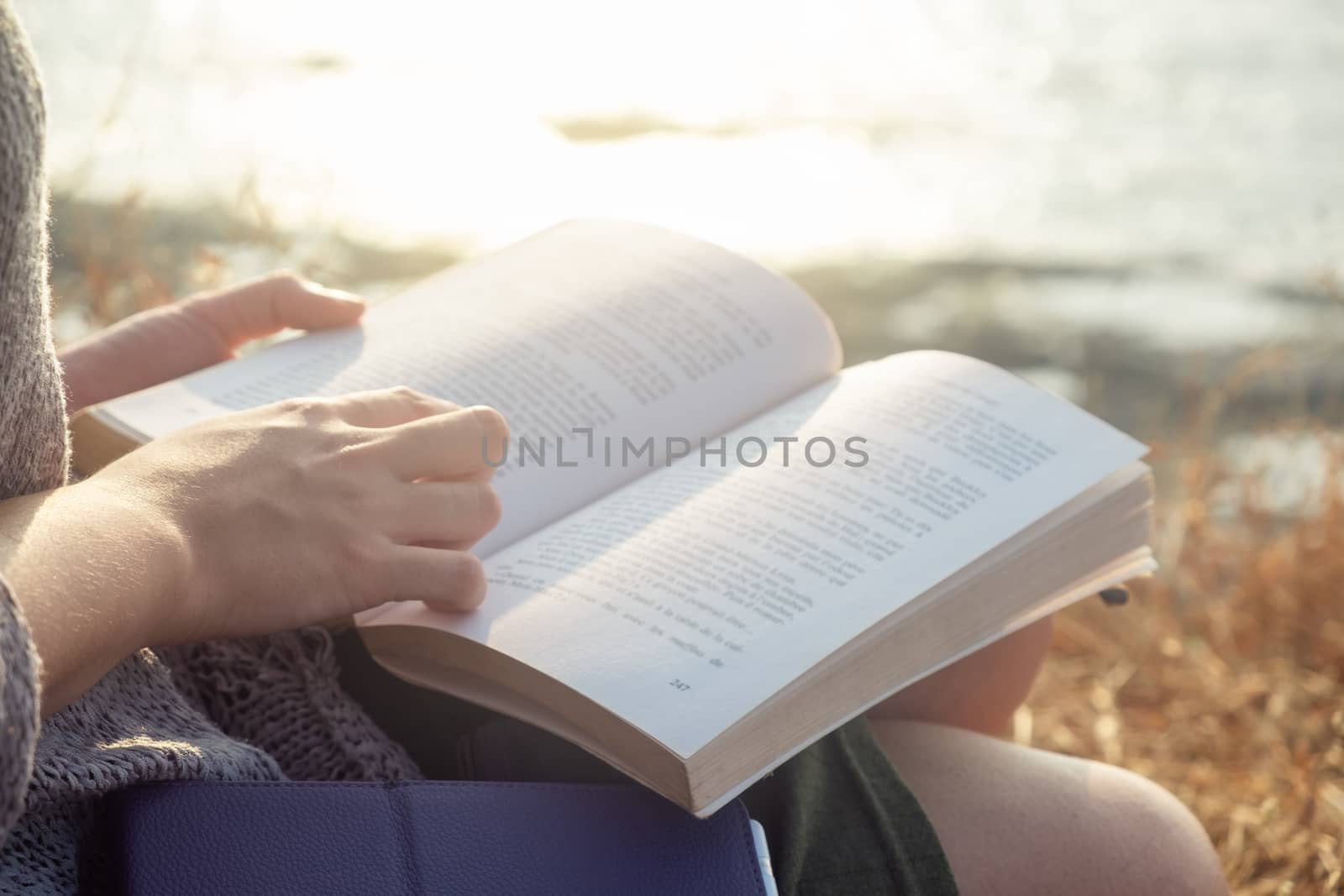 Young Woman Reading Book While Sitting Outdoors, close-up view