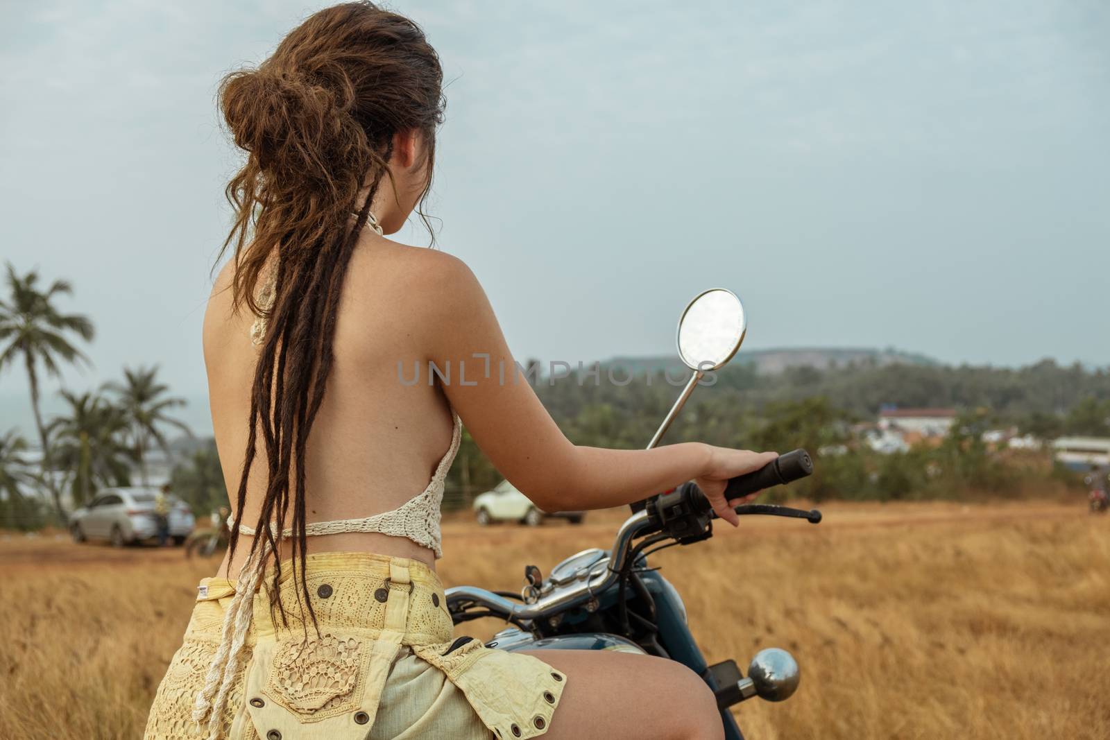 A woman sits on a motorcycle in a field by snep_photo