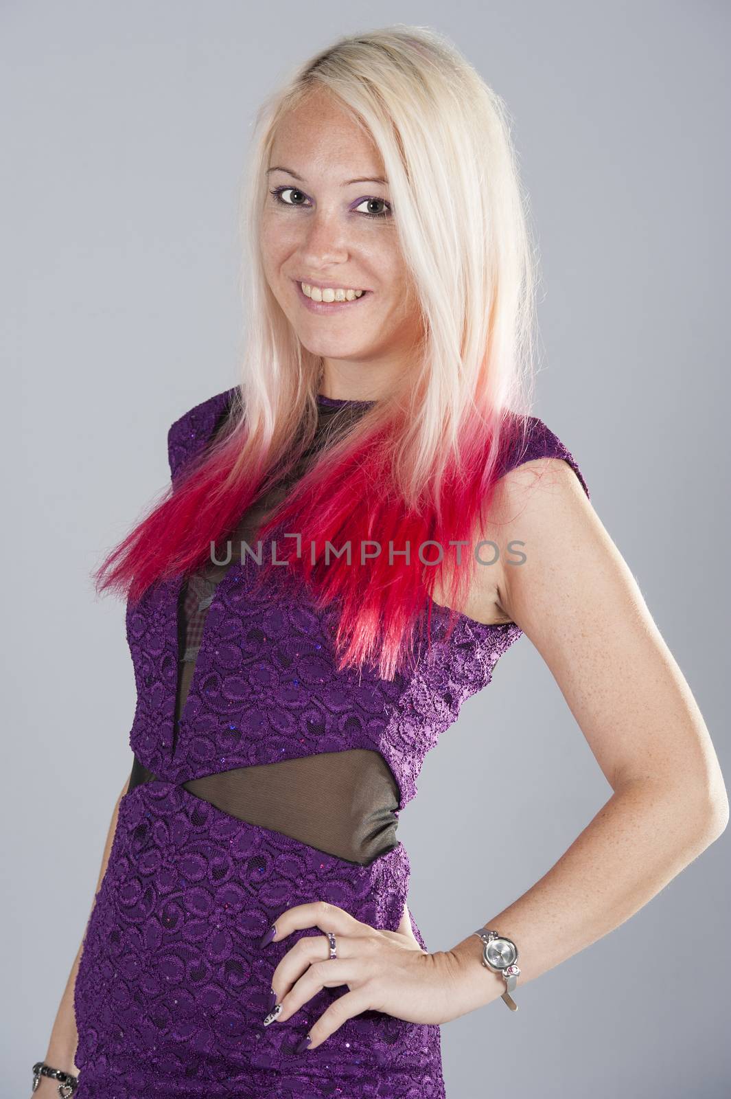 Beautiful young happy blond punk girl posing wearing purple isolated on blue background