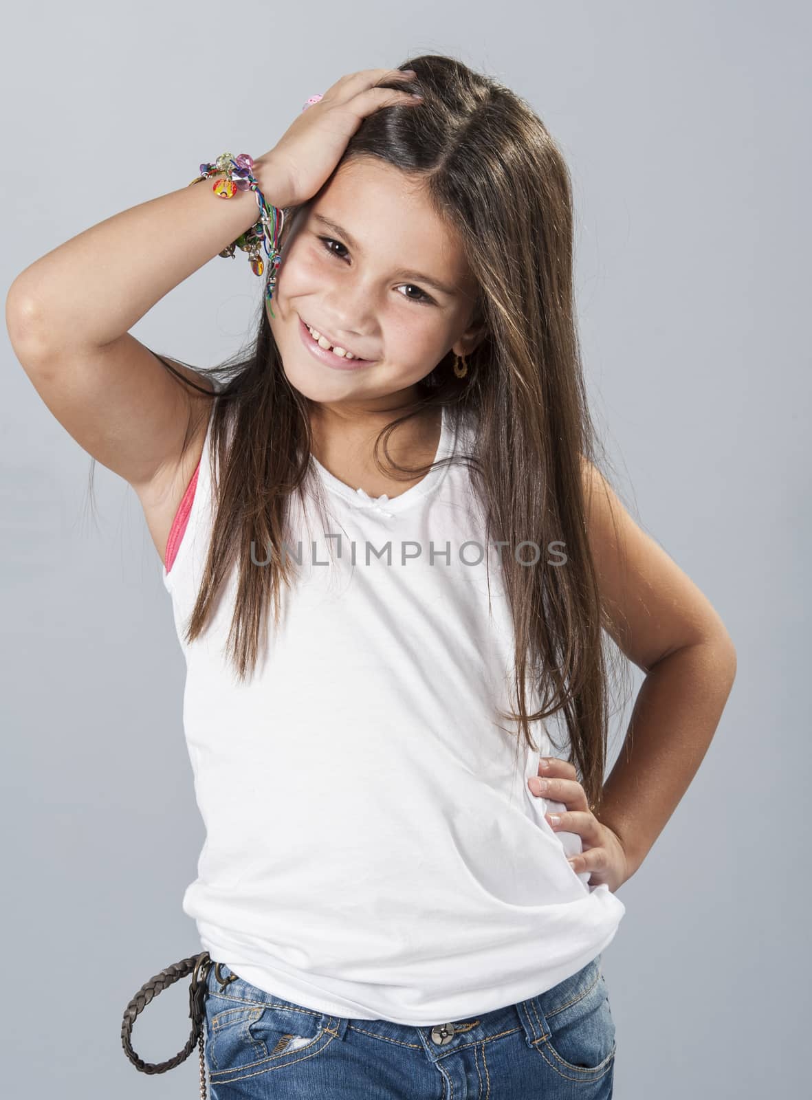 Beautiful young latino brunette female child with long hair posing in studio isolated on a blue background