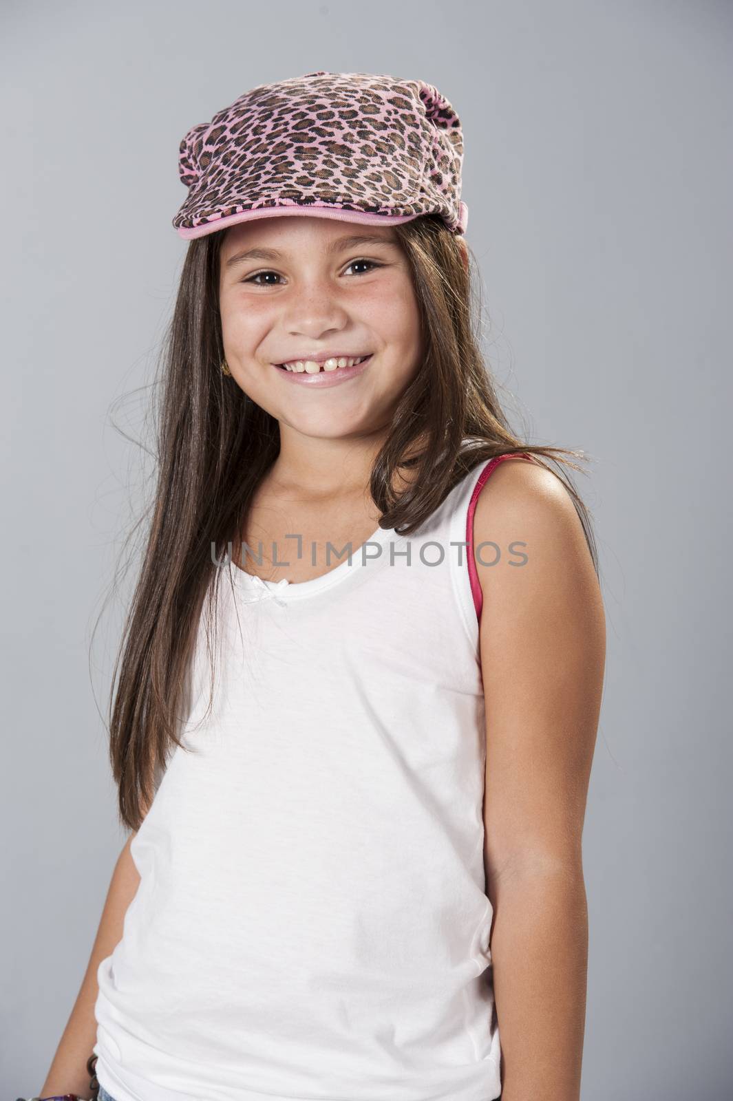 Beautiful young latino brunette female child with long hair posing in studio isolated on a blue background