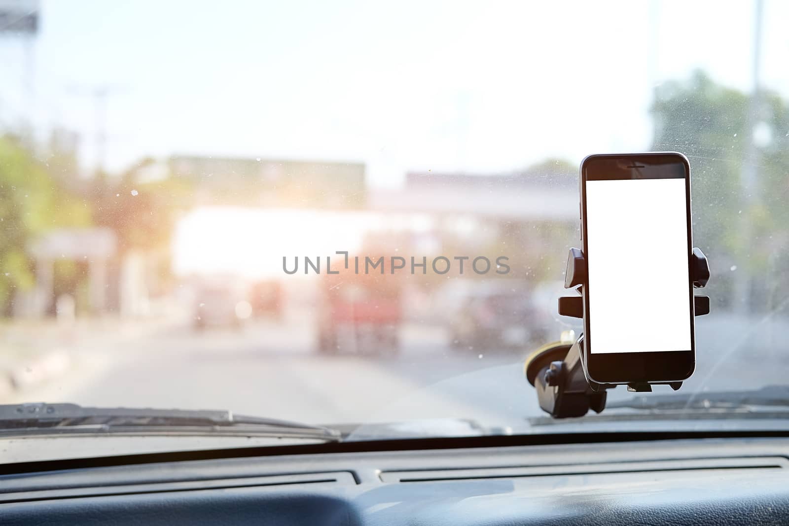 Cropped shot view The driver uses the phone while driving. Modern smart phone with round edges. Isolated screen for mockup. Car navigation display in background. 