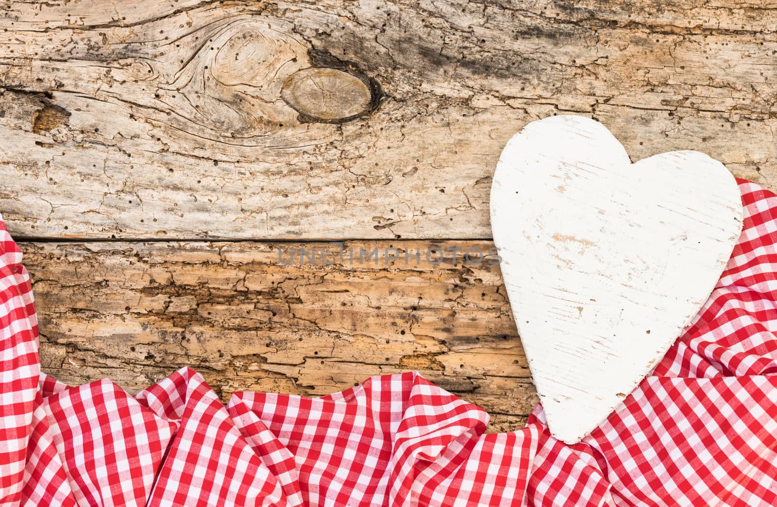 Romantic background with white heart and red fabric border on rustic wood with copy space