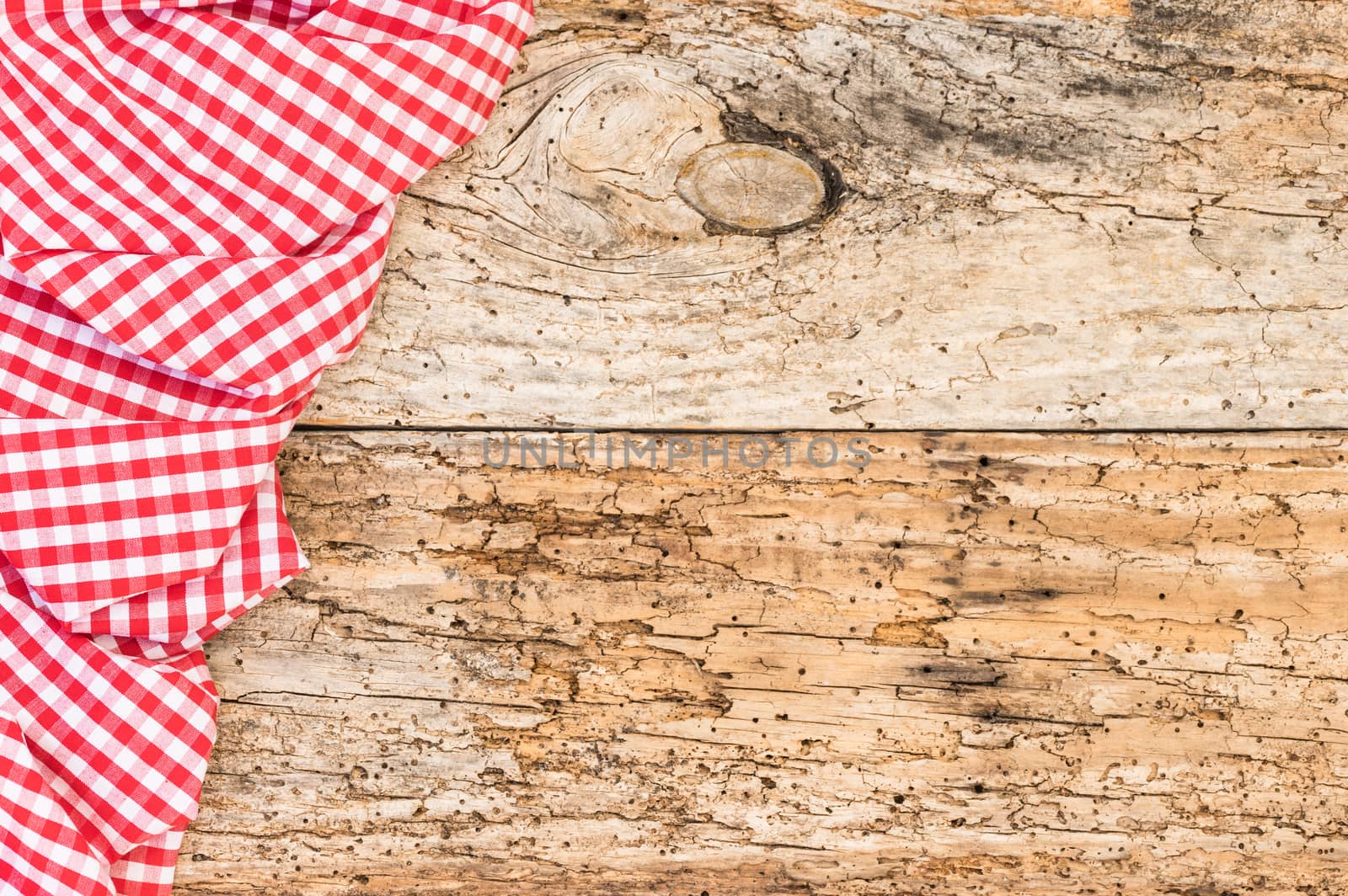 Rustic old wooden table surface with red checkered cloth, top view