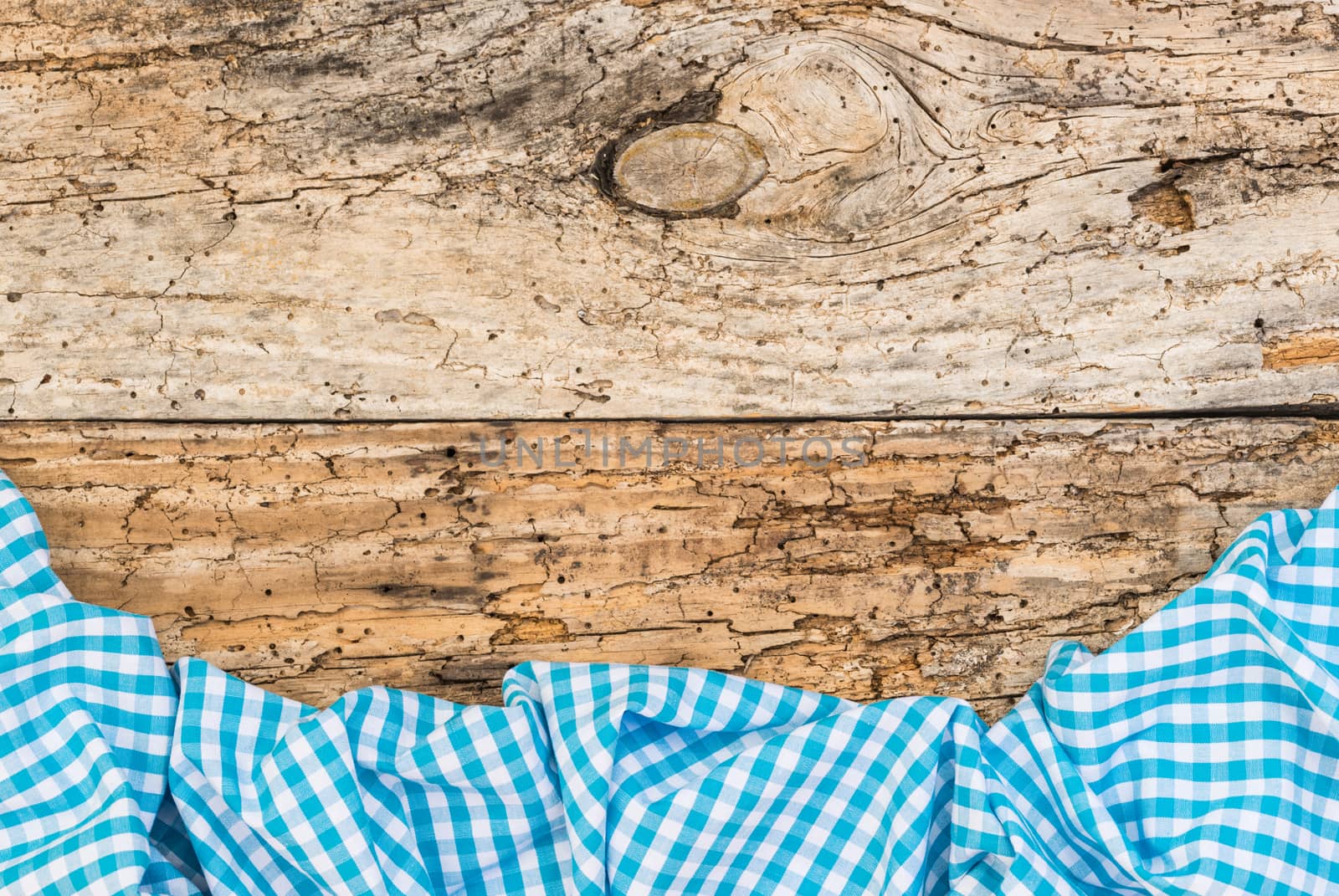 Rustic old wooden table surface with blue checkered cloth, top view