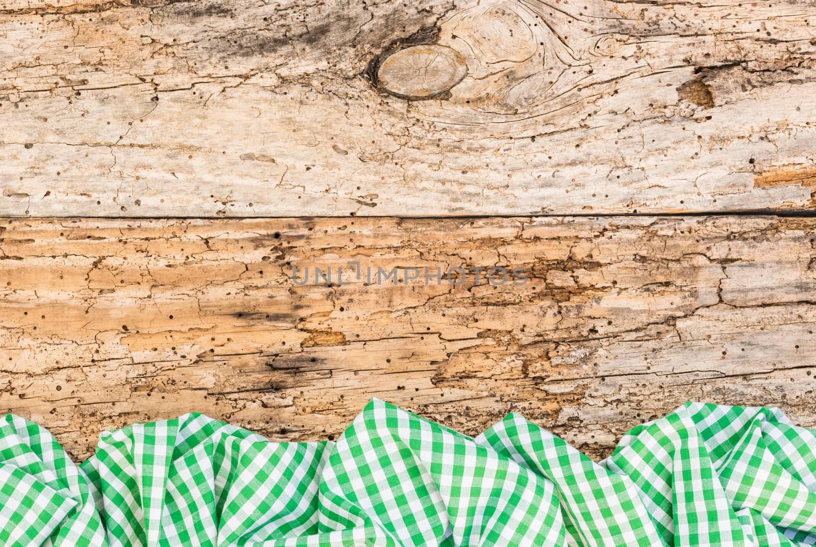 Old wooden table surface with rustic green checkered cloth, top view