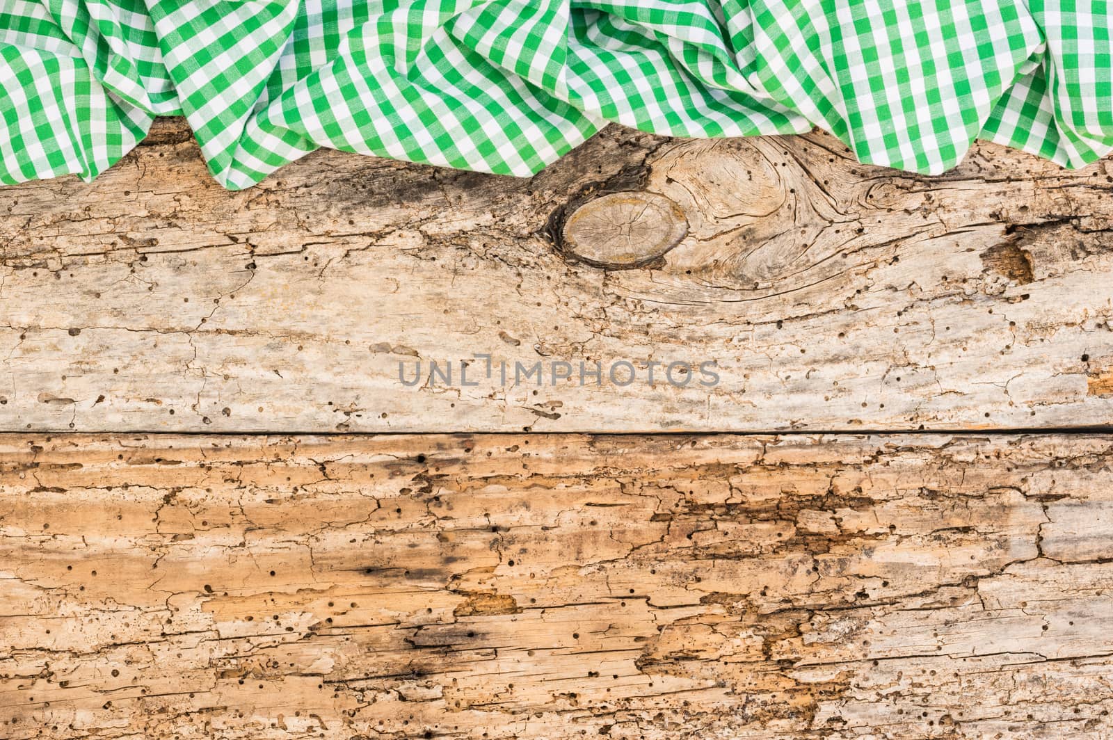 Rustic old wooden table surface with green checkered cloth, top view