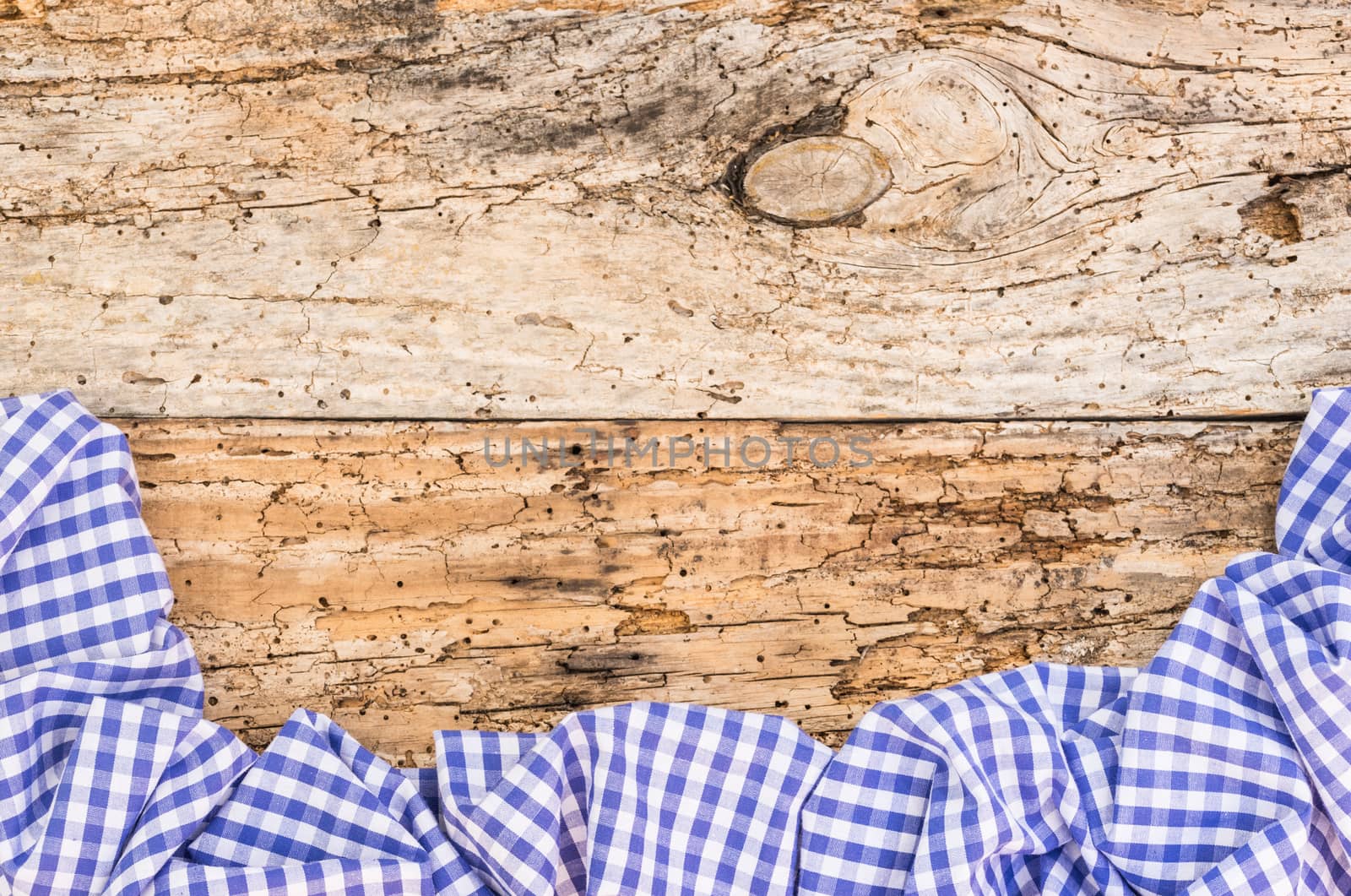 Old wooden table surface with rustic blue checkered cloth, top view