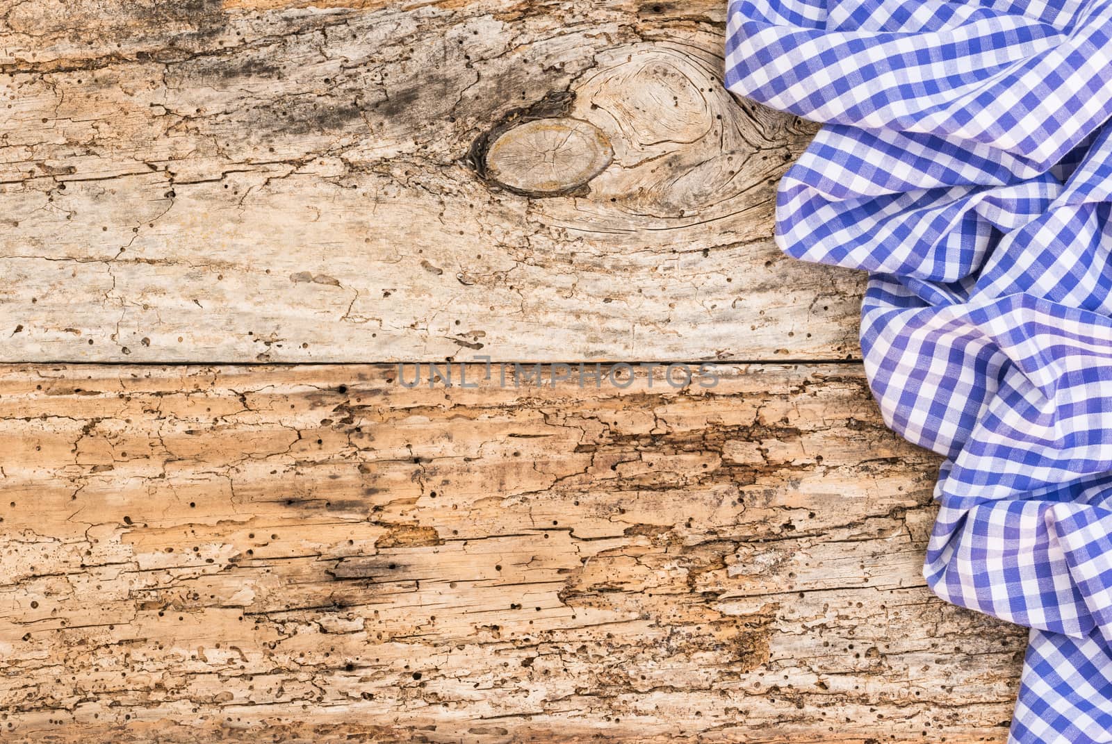 Old wooden table surface with rustic blue checkered cloth, top view