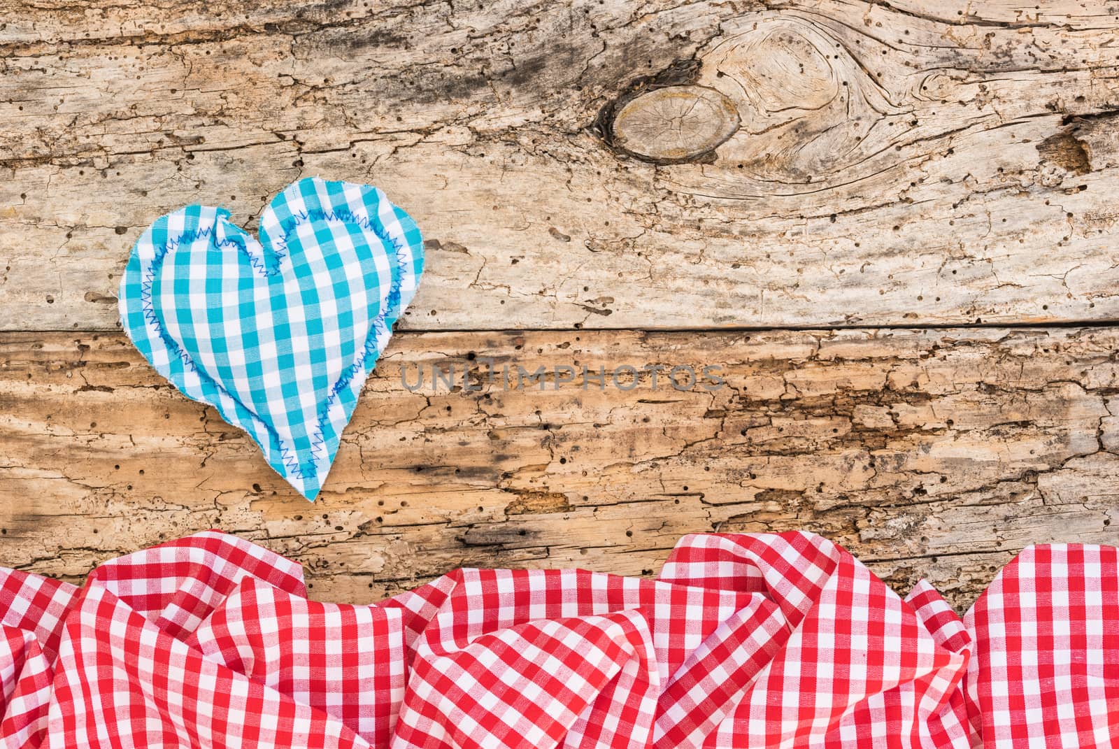 Blue fabric heart with red checked pattern frame on vintage wood with copy space