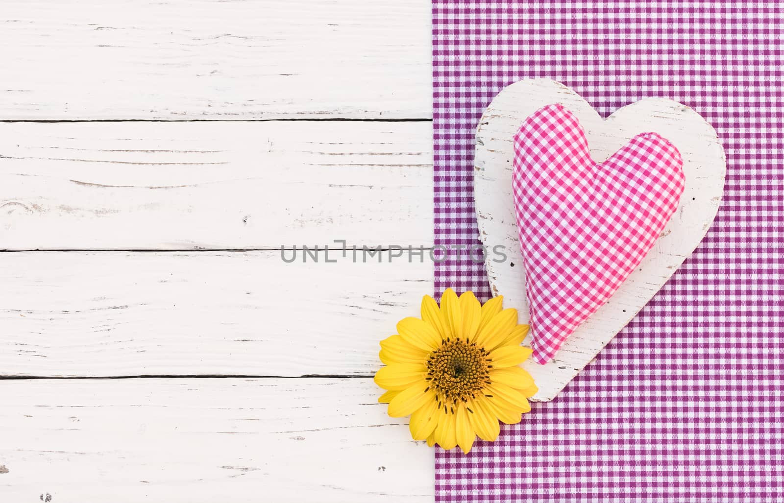 Cute pink heart and flower on purple fabric and white wooden background