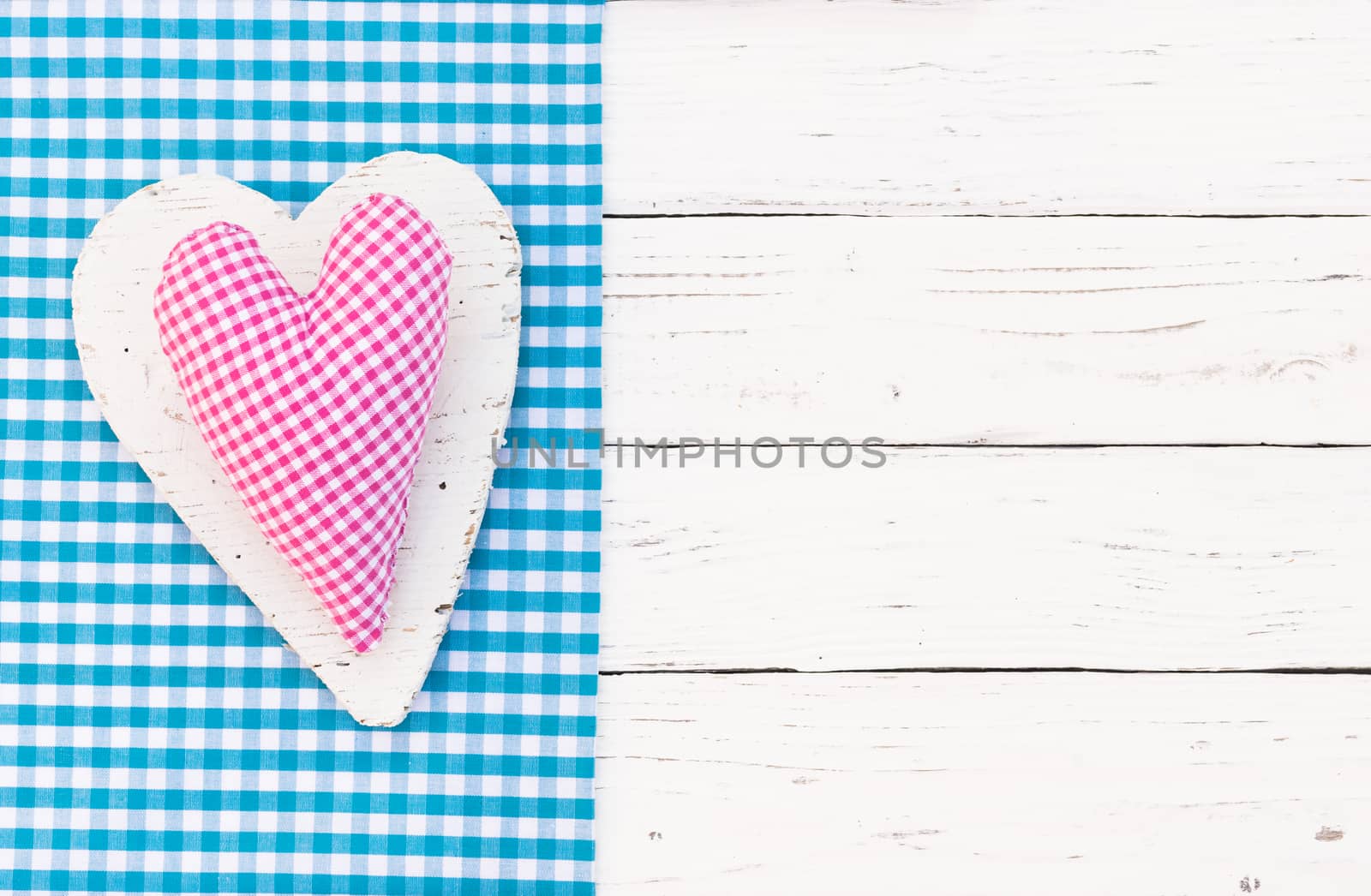 Pink heart on blue fabric border and white wood background with copy space