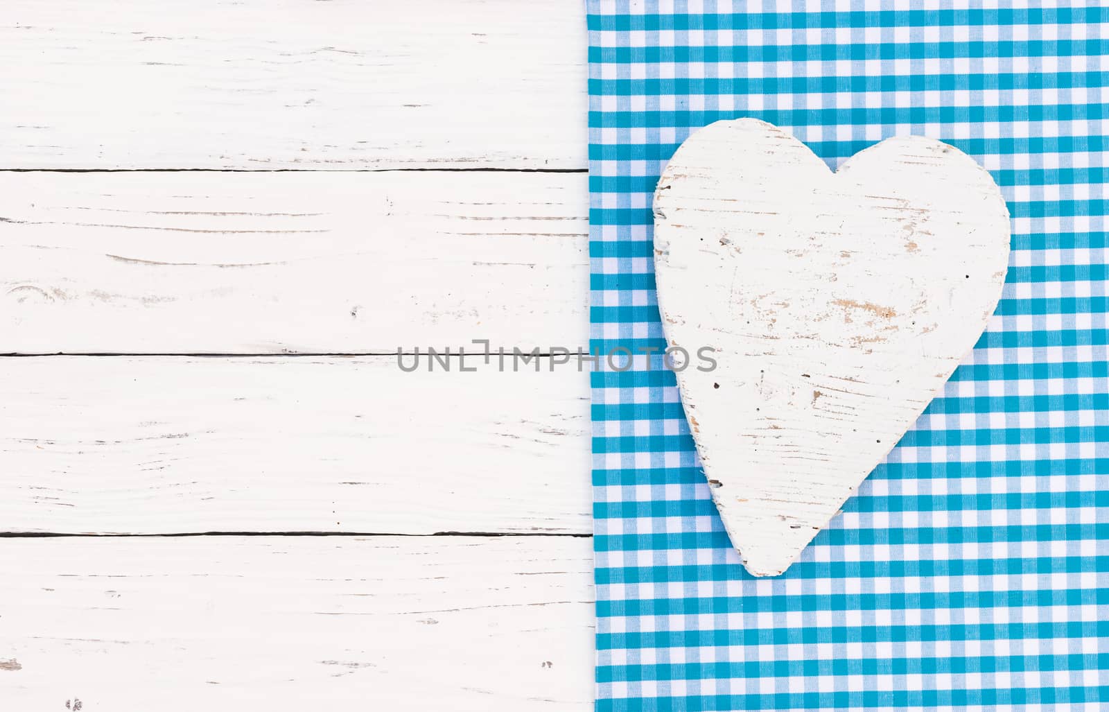 White wooden heart on blue fabric and wood background with copy space
