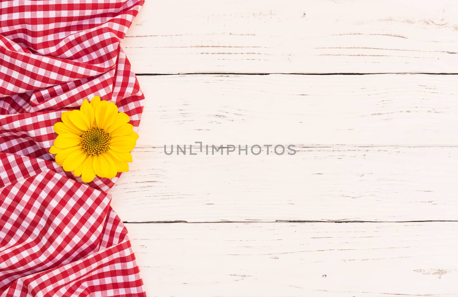 Red checked tablecloth with blossom on white wooden background with copy space