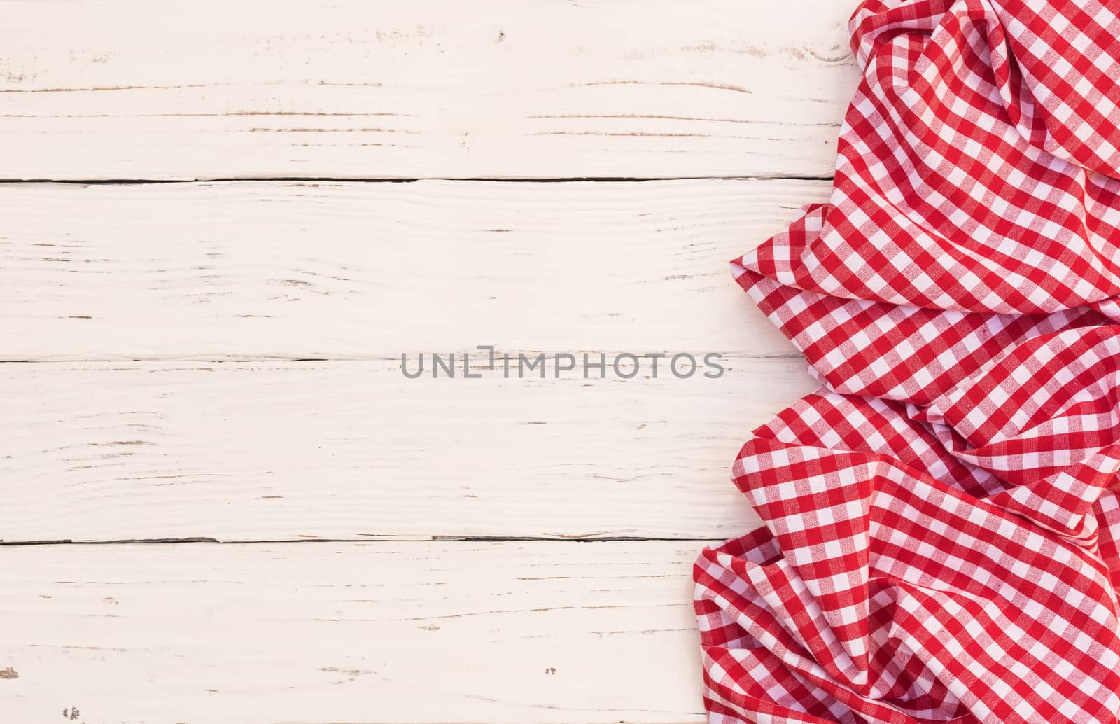 Rustic white wooden table surface with red checkered cloth, top view